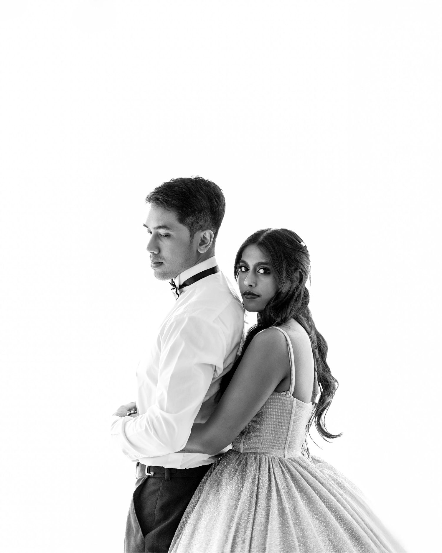 Black and white portrait of a couple in formal attire, man in white shirt, woman in elegant gown, studio photo.