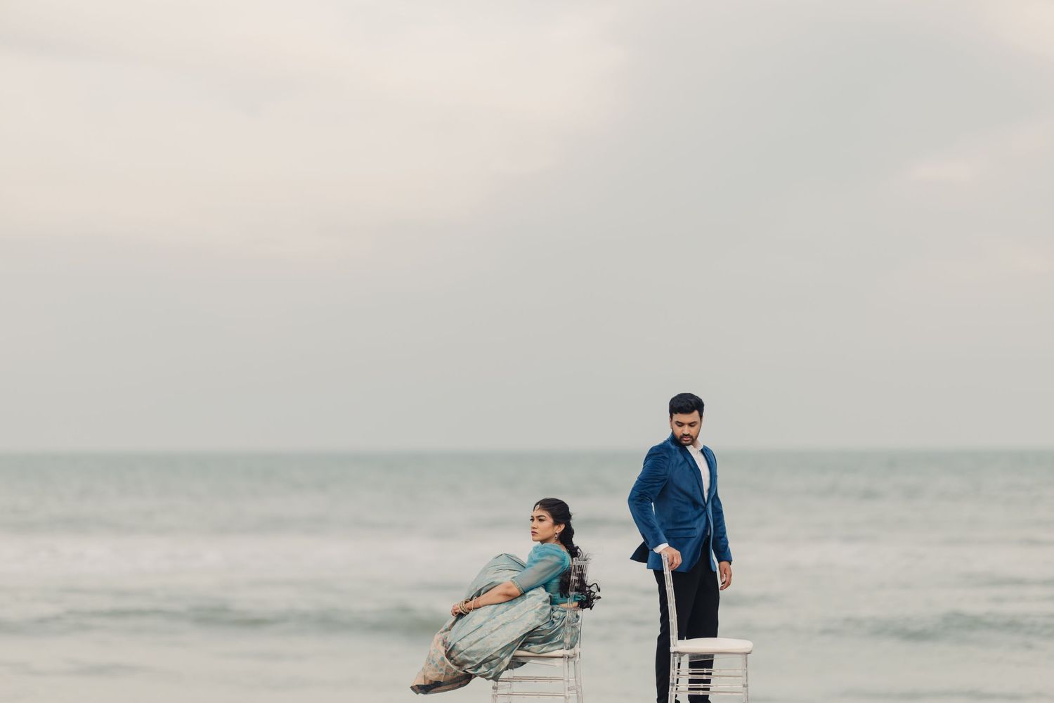 Two people enjoy a peaceful moment by the ocean shore with a lifeguard chair in the foreground.