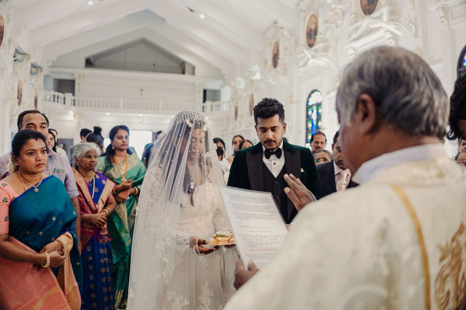 Guests gather in an elegant white ballroom with classical architectural details and vaulted ceilings.