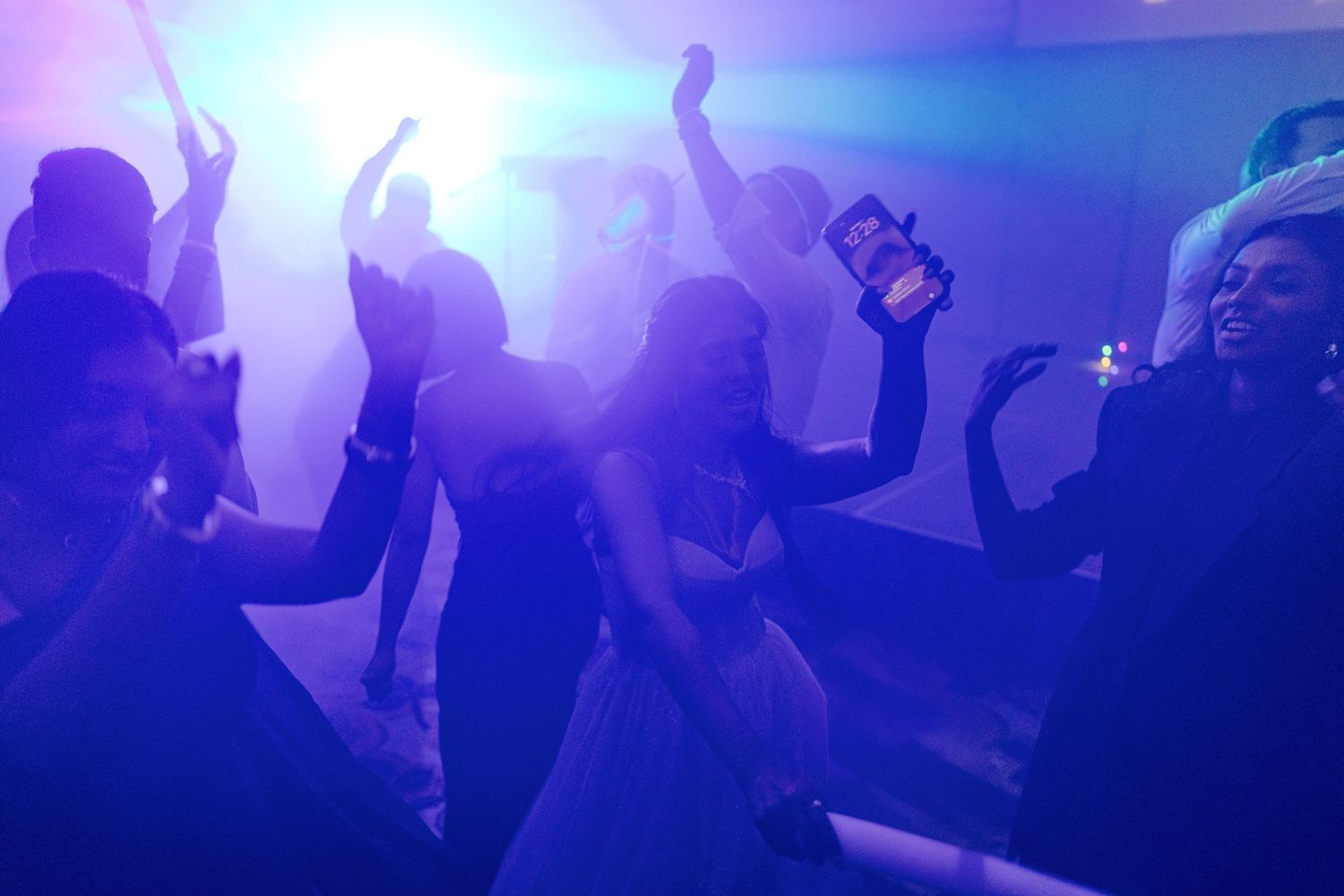 Guests dancing under purple and blue lights at a lively wedding reception party.