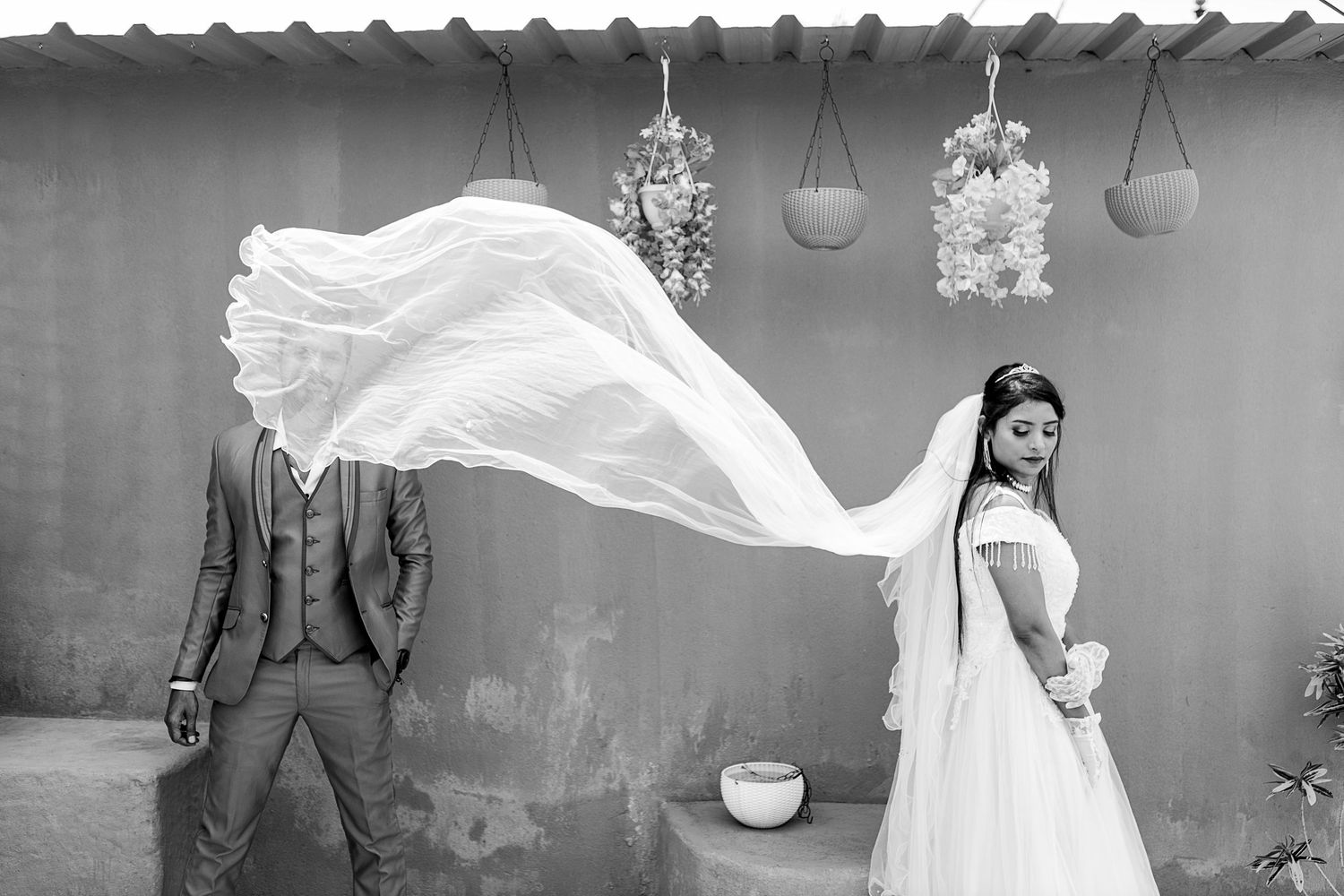 Wedding couple with flowing white dress against neutral background.