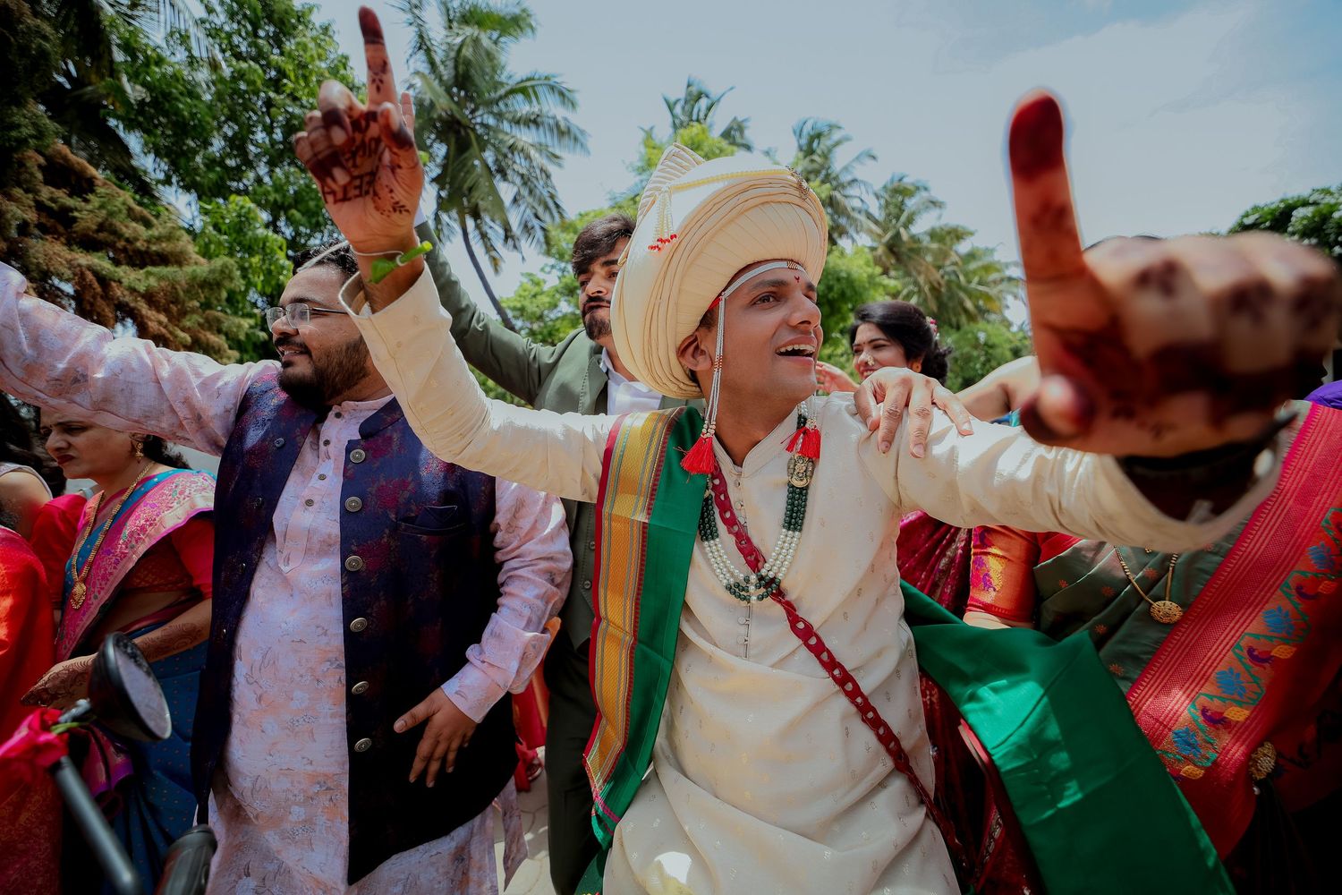 A group of people dance and celebrate outdoors at a summer festival wearing colorful traditional costumes.