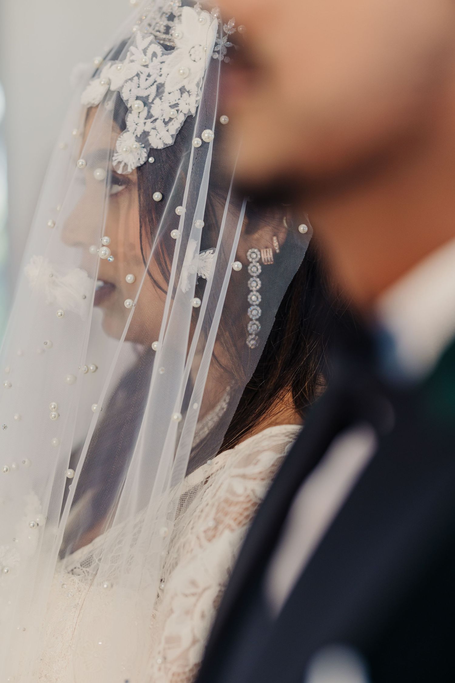 Close-up detail of delicate lace and crystal embellishments on a white wedding veil.
