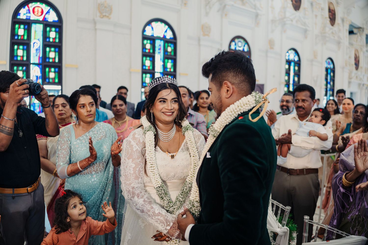 Wedding celebration inside historic church with stained glass windows and guests applauding.