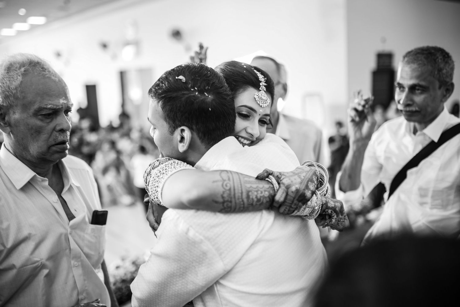 A series of black and white candid wedding photos showing emotional embraces and celebrations at a reception.