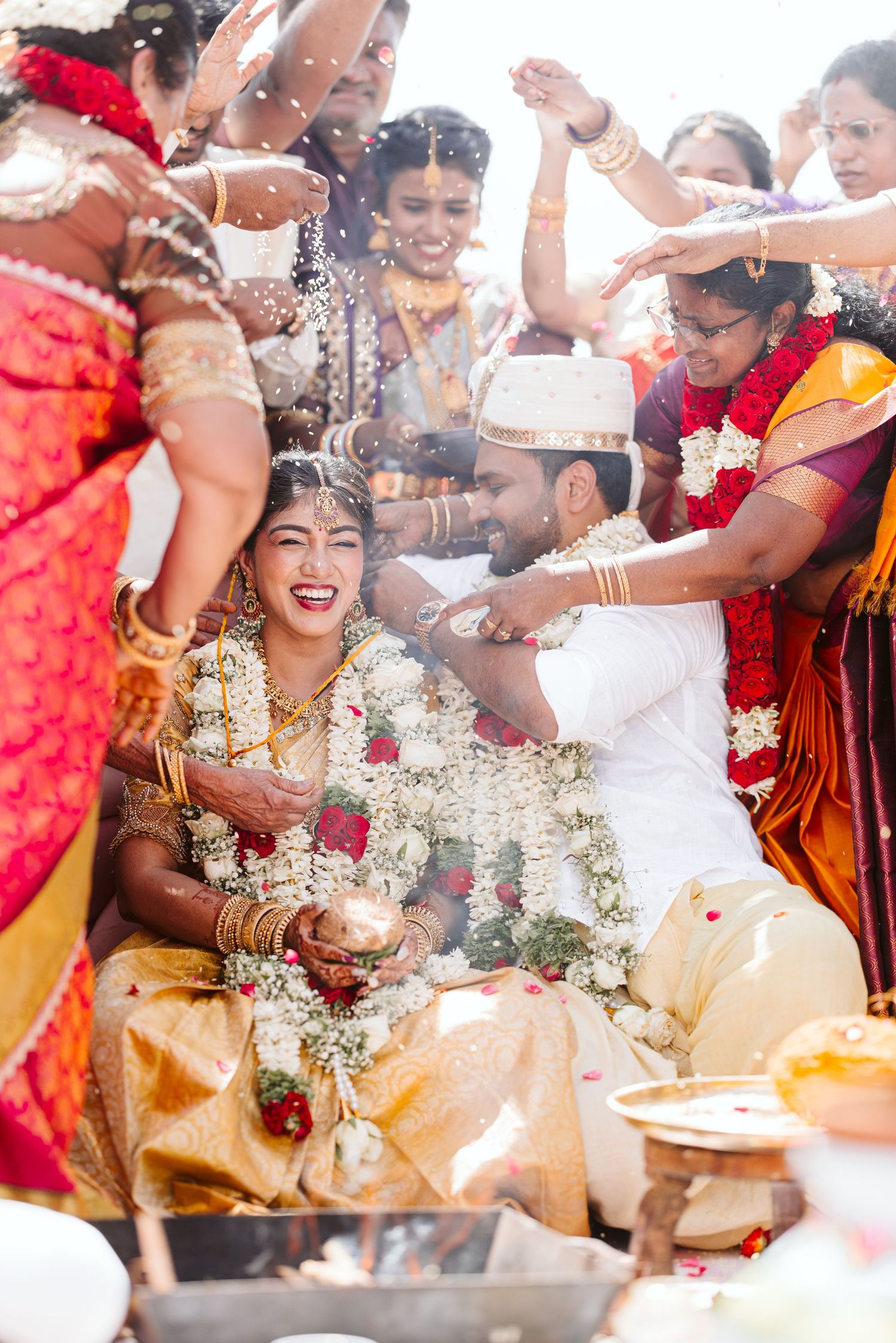 Joyful celebration at a traditional Indian wedding ceremony with guests showering flower petals and blessings.