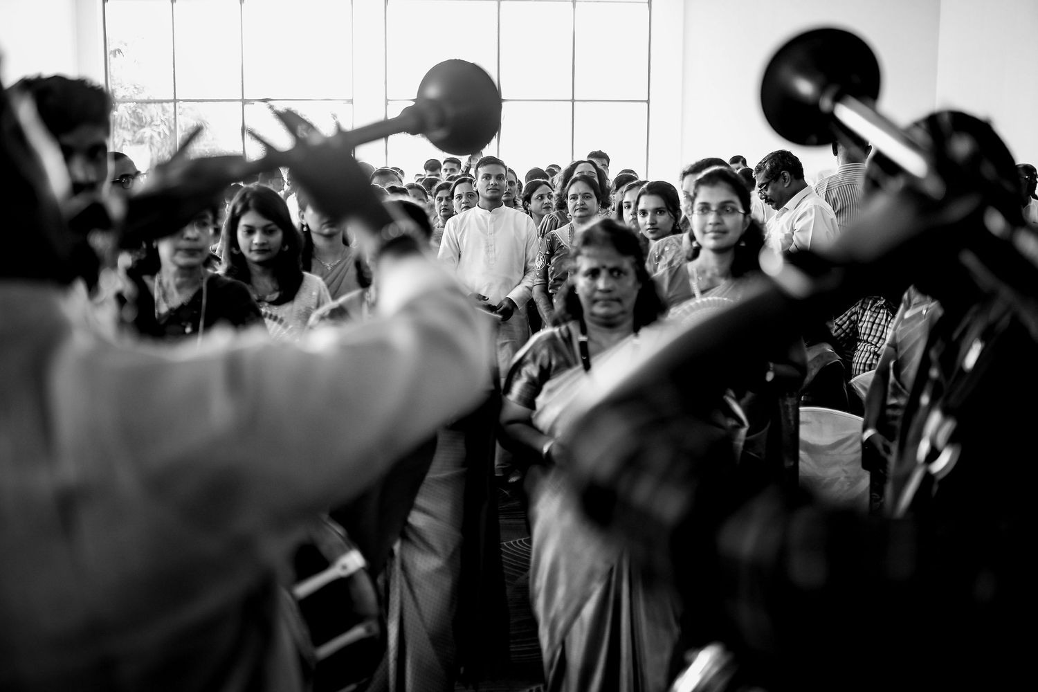 Black and white photo of an energetic crowd at a concert with raised hands and silhouetted figures in motion.
