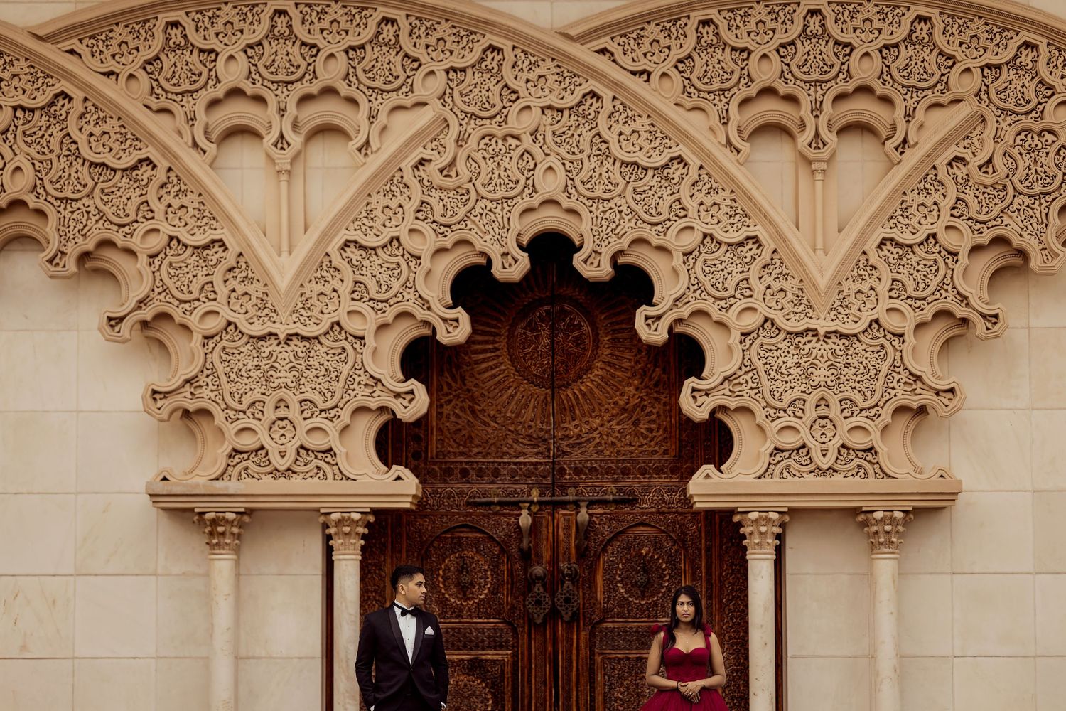 Ornate white archways with intricate Moorish architectural details line a corridor in a historic building.