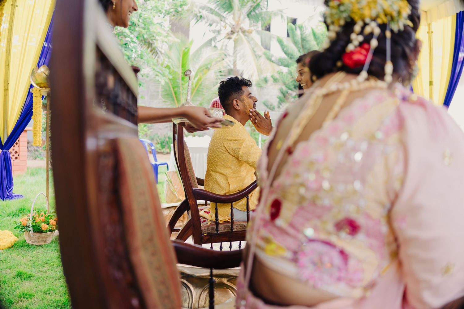 A couple shares a romantic moment during their wedding celebration in a garden setting with blurred floral decorations.