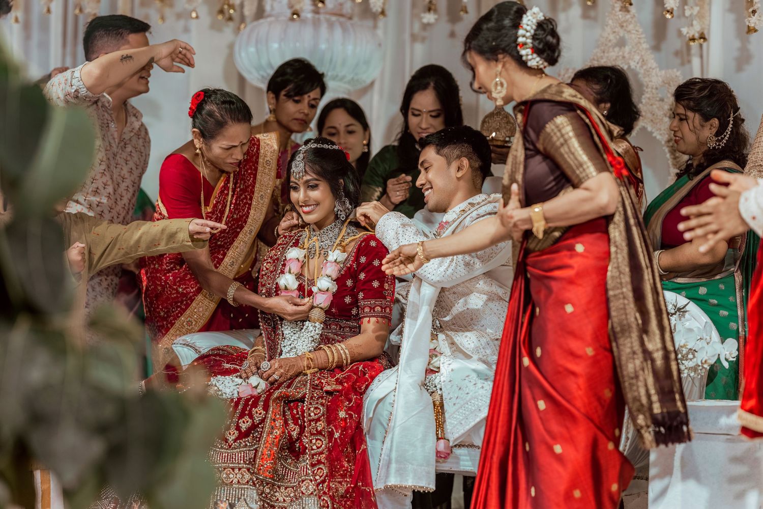Vibrant Indian wedding ceremony with bride in red lehenga surrounded by guests in traditional sarees and attire.