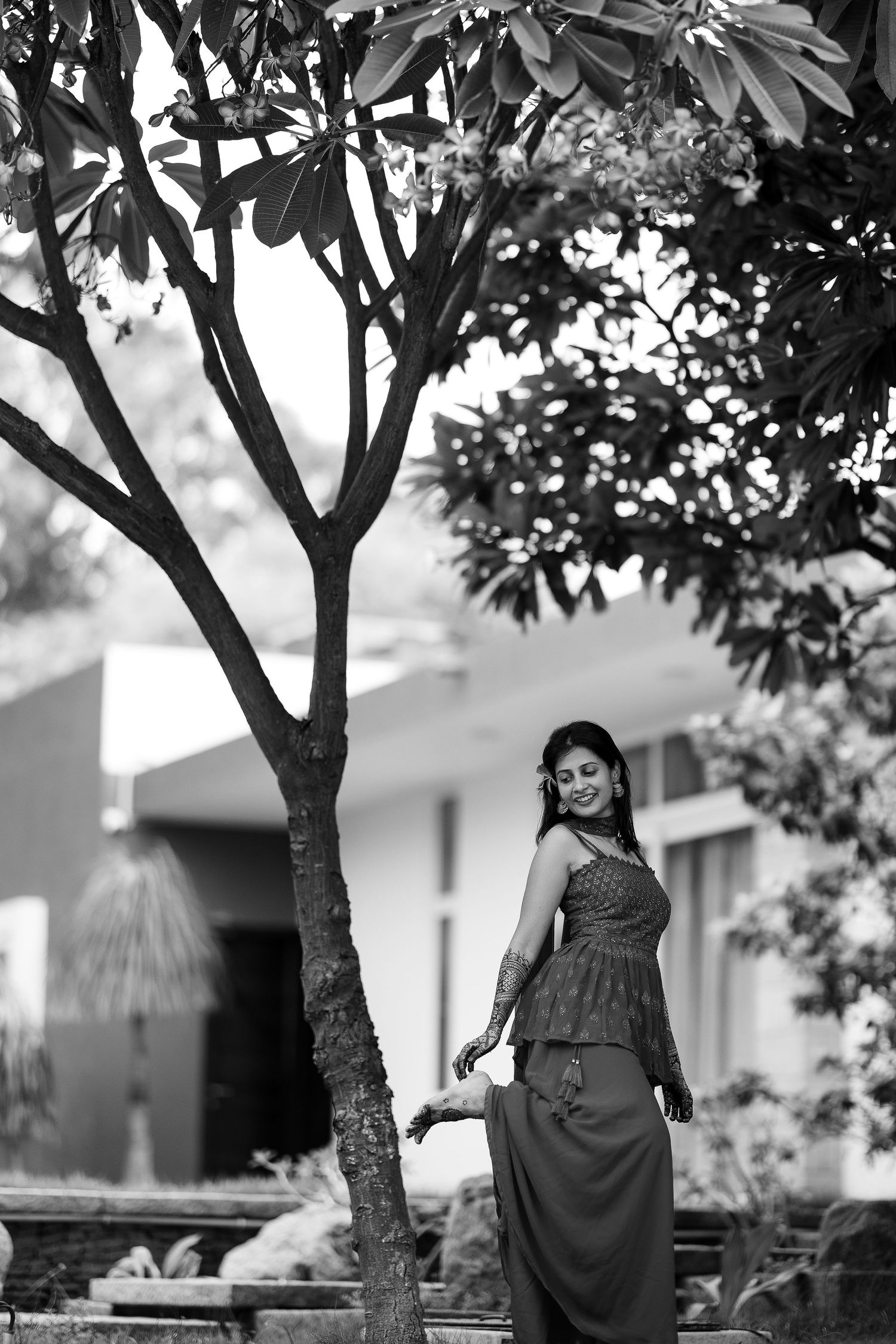 A black and white photo sequence showing a person in a dress walking beneath trees in a garden setting.