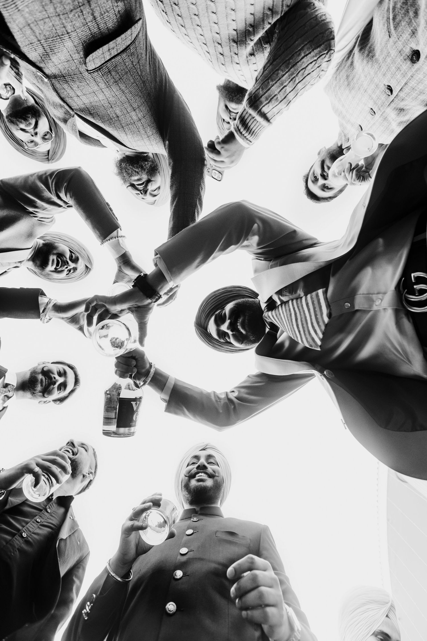 Black and white photo showing a group of people laughing and celebrating together in an upward-looking perspective.