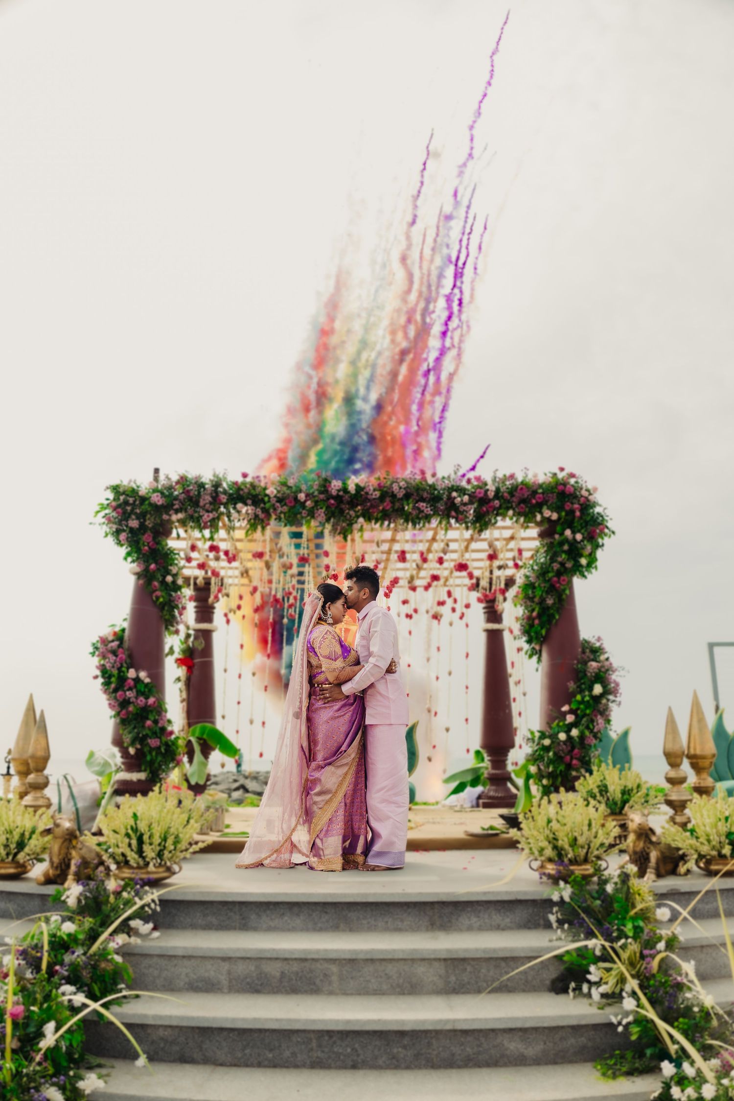Outdoor wedding setup with floral arch and colorful streamers against white backdrop.