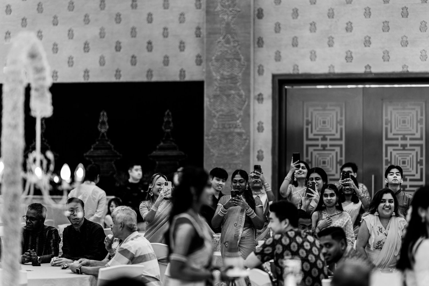 Black and white photo of guests celebrating at an elegant Indian wedding reception, capturing joyful moments.