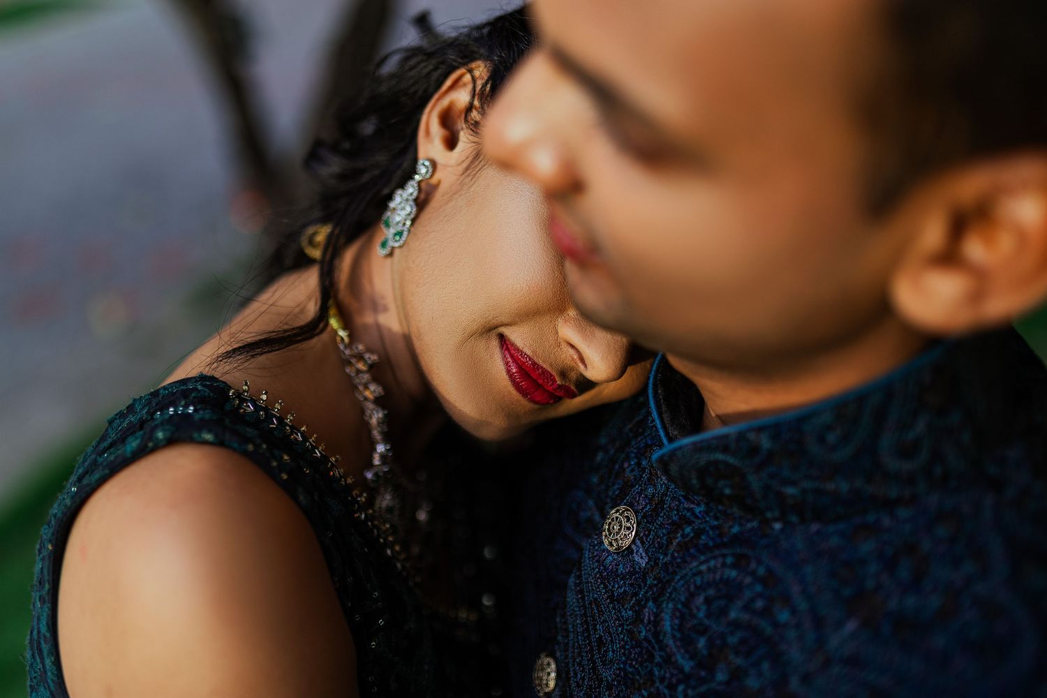 A couple shares an intimate romantic moment in a garden setting during a golden hour photoshoot.