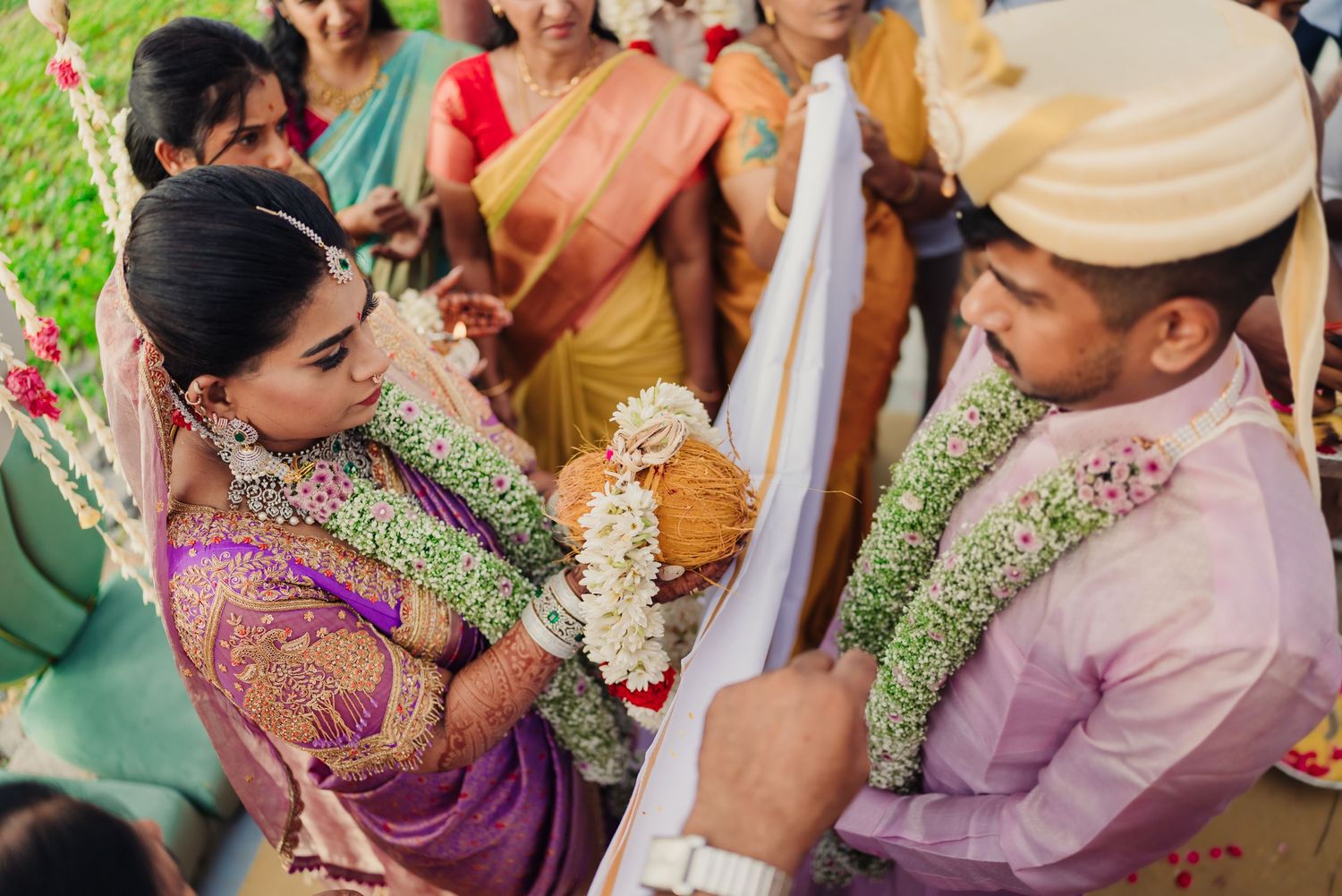 A traditional Indian wedding ceremony with participants wearing floral garlands and colorful traditional attire.