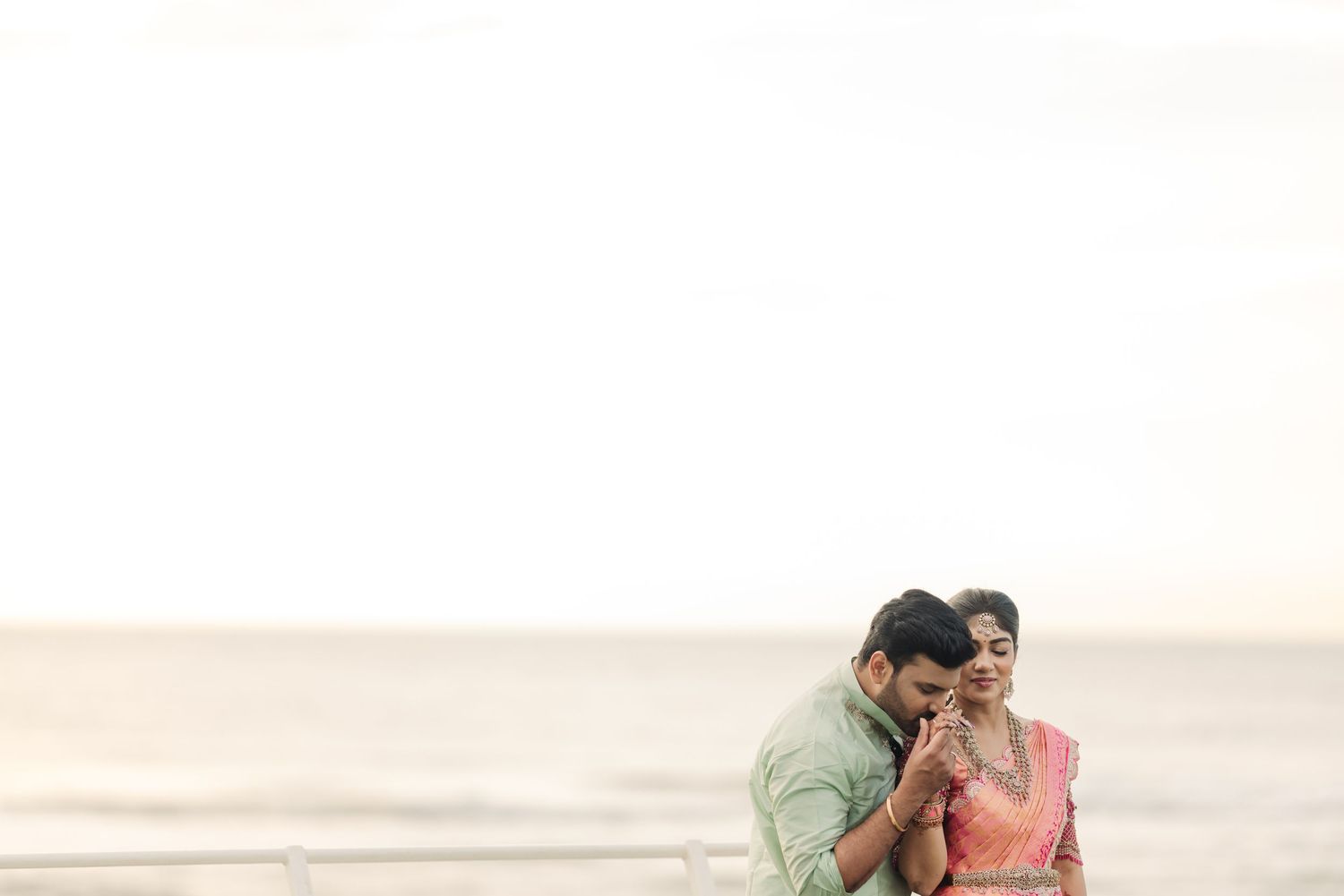 Romantic beach photoshoot with soft sunset lighting and ocean backdrop.