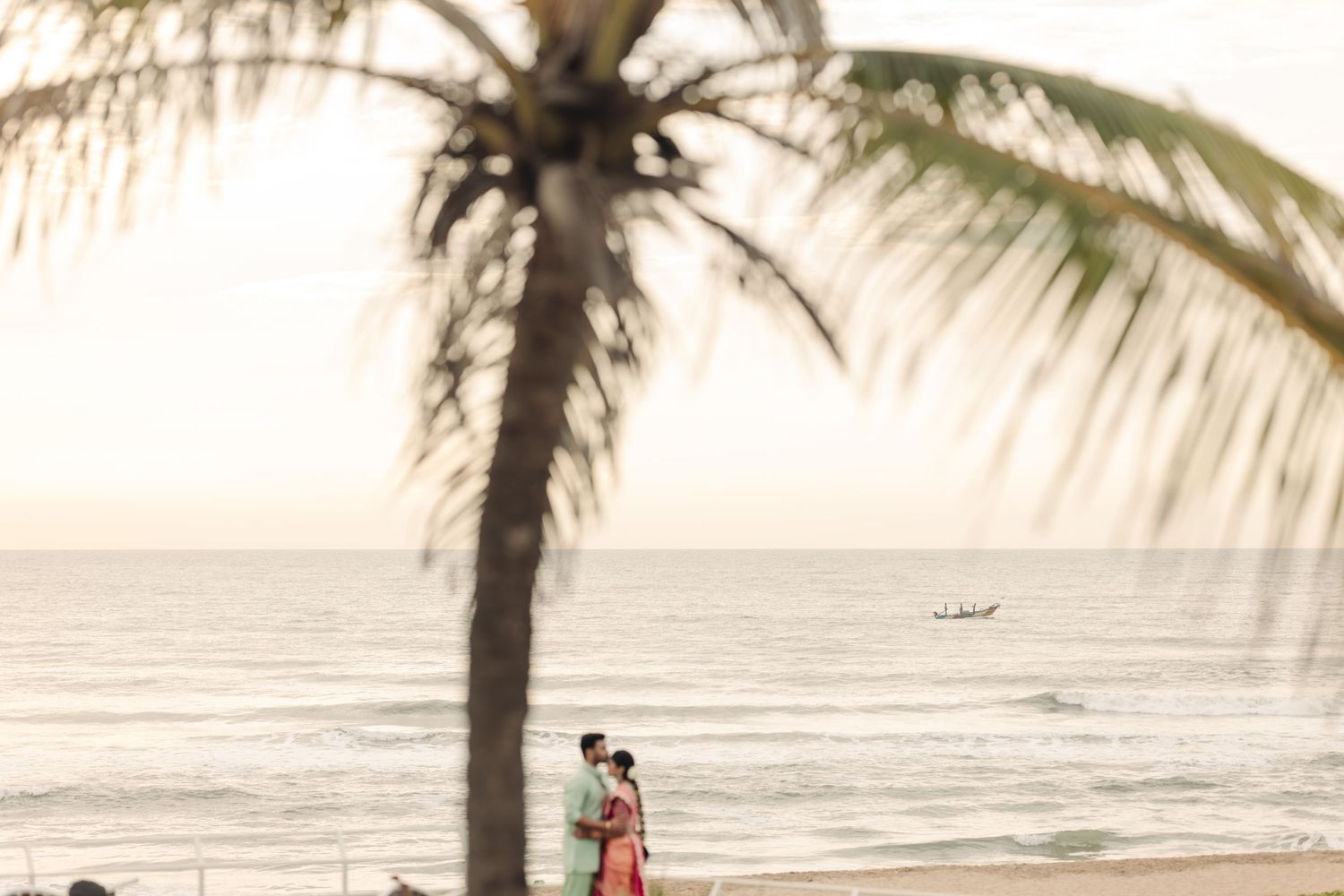 Palm trees frame a romantic beach scene at golden hour.