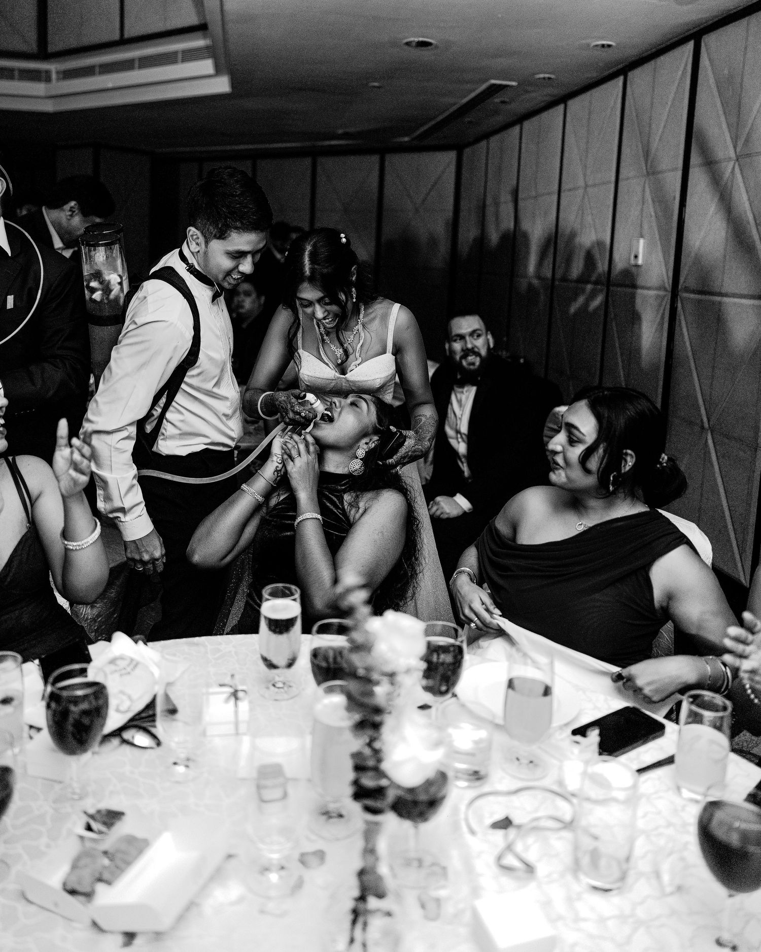 Black and white photo of guests celebrating at an elegant dinner party, gathered around a candlelit table.