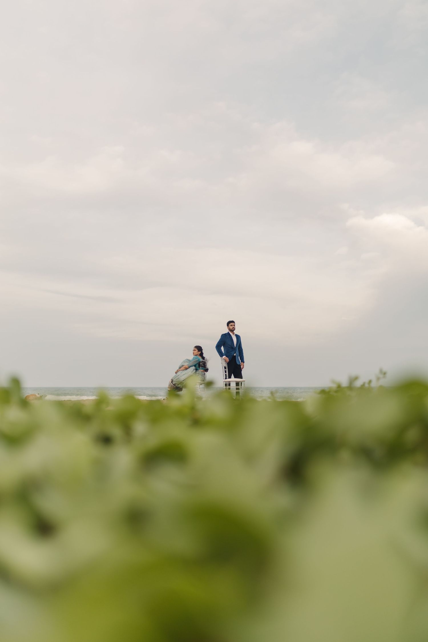 Minimalist landscape with soft focus foreground and figures silhouetted against cloudy sky.