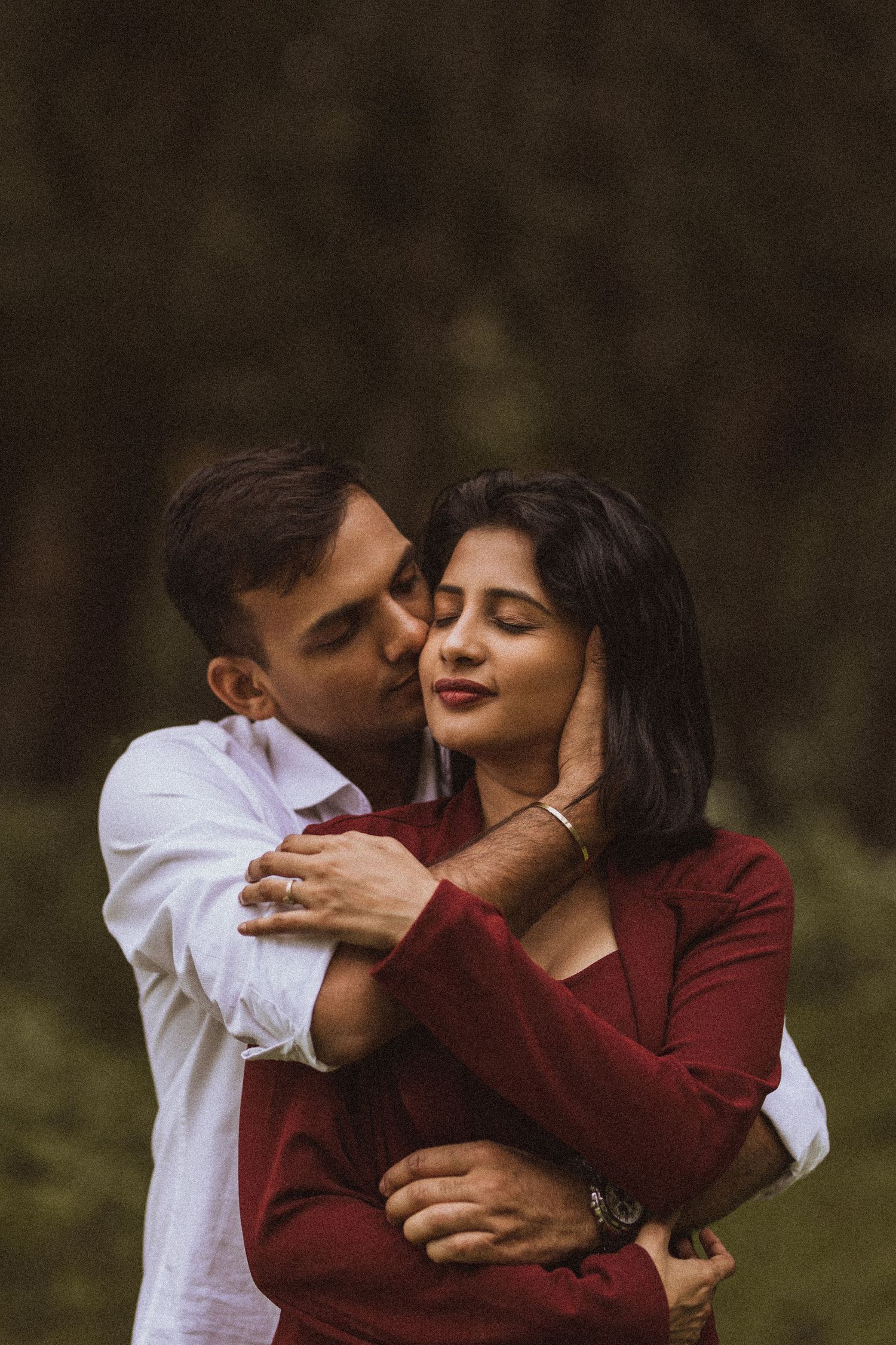 A romantic couple shares tender moments in a series of intimate embraces while wearing burgundy and white outfits outdoors.