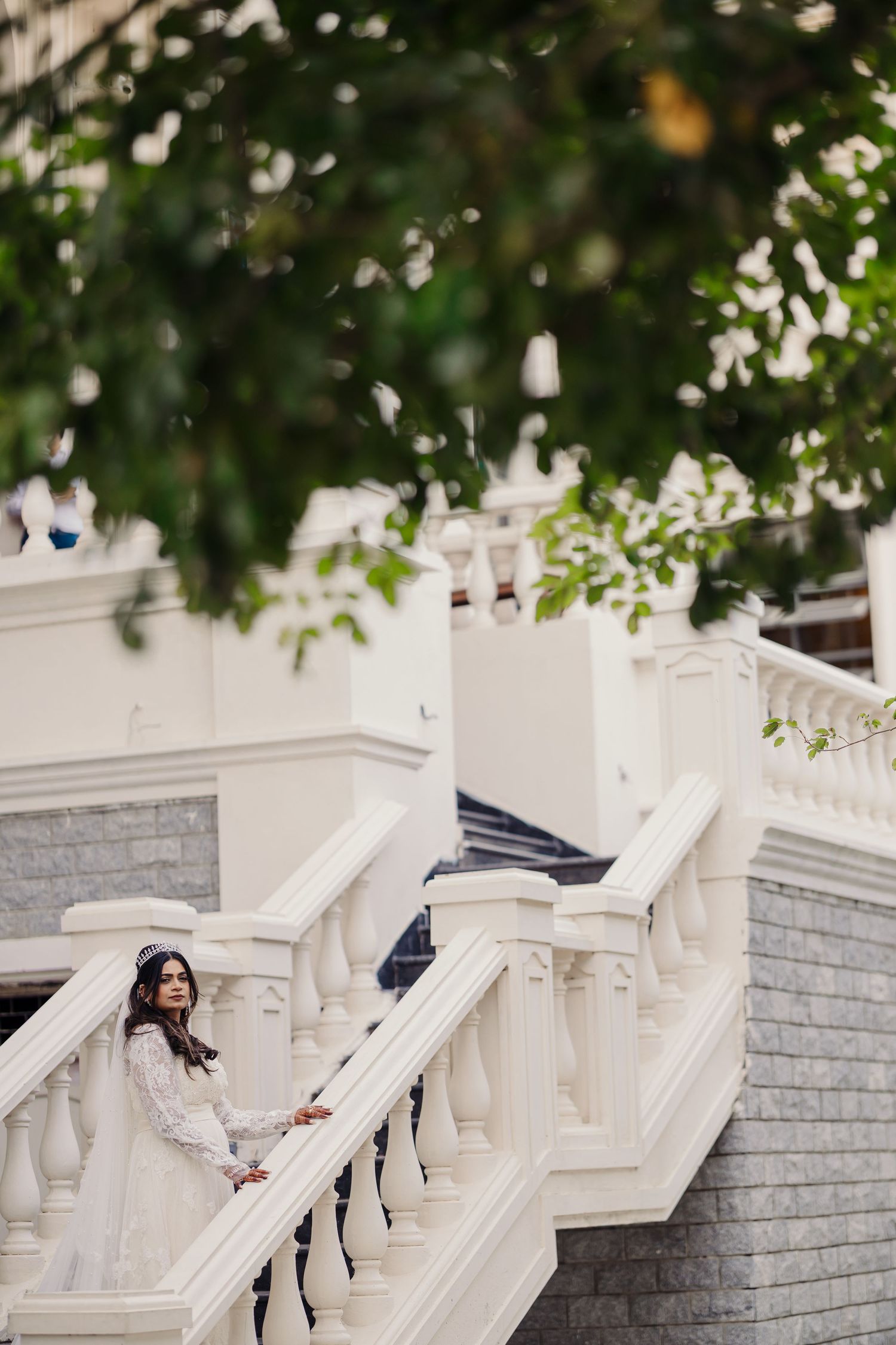 A series of white marble steps with decorative railings and greenery overhead creates an elegant architectural scene.