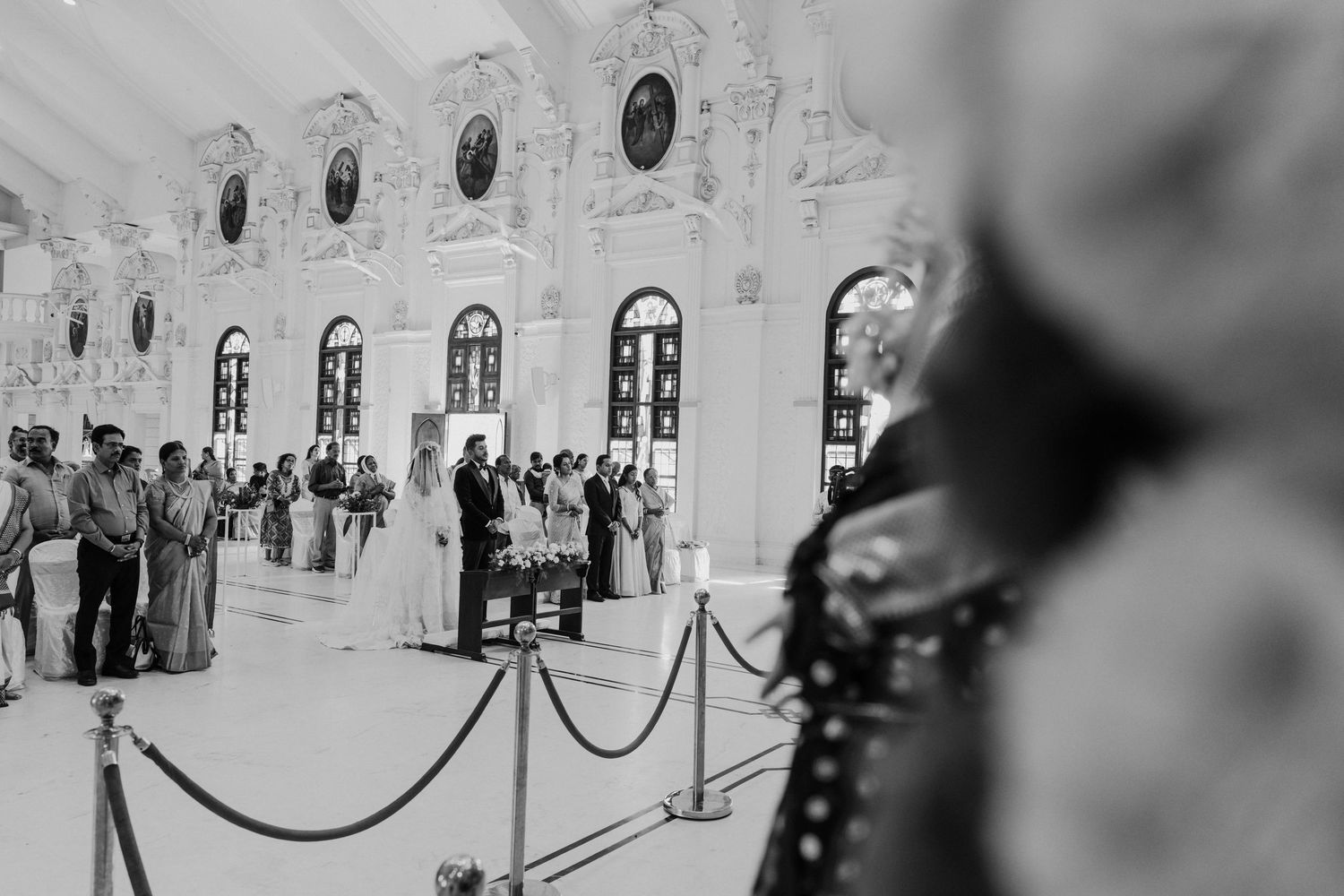 Elegant ballroom interior with ornate architecture and chandeliers in black and white photography.