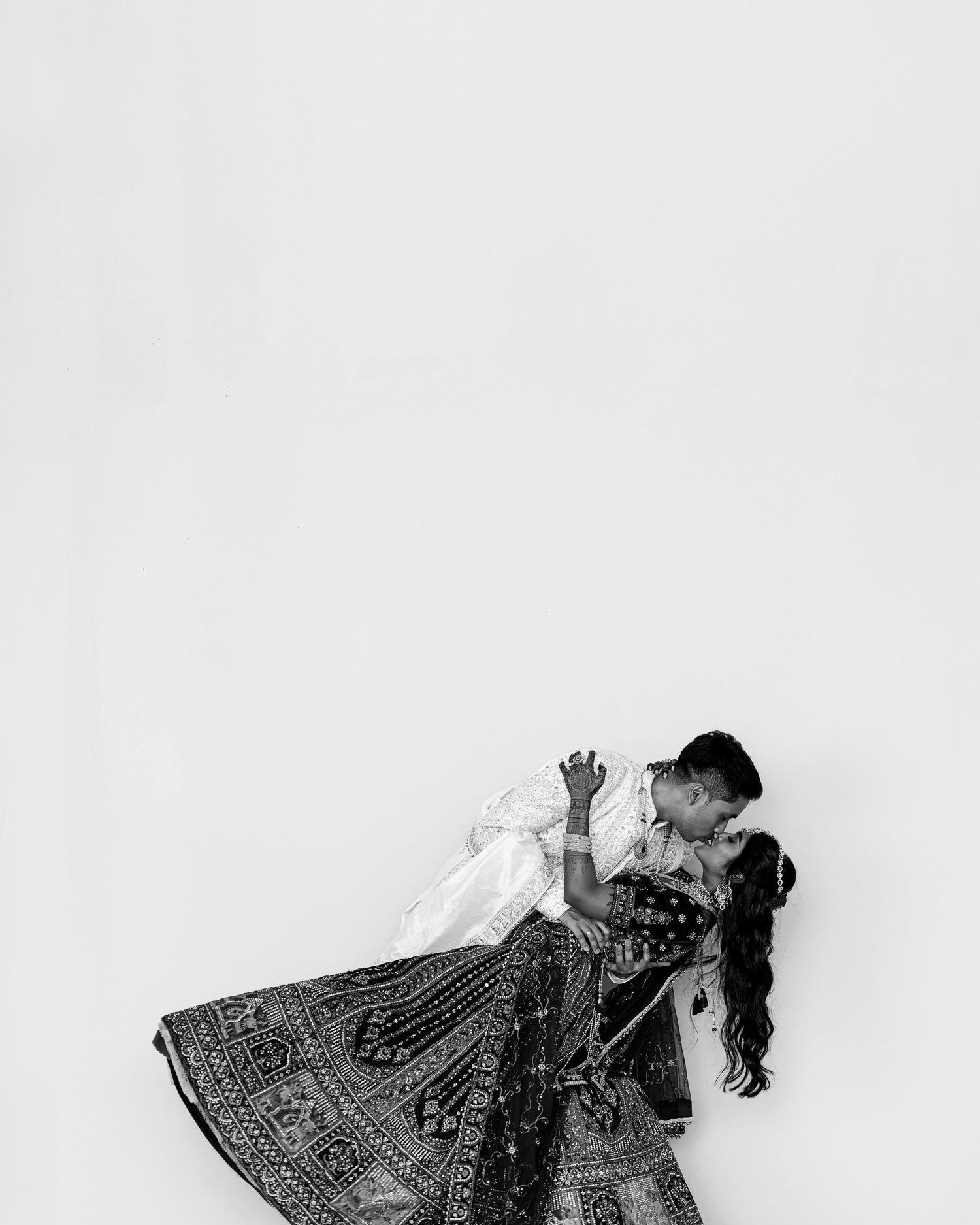 Black and white photo of a couple in traditional Indian attire sharing a romantic dip dance pose.