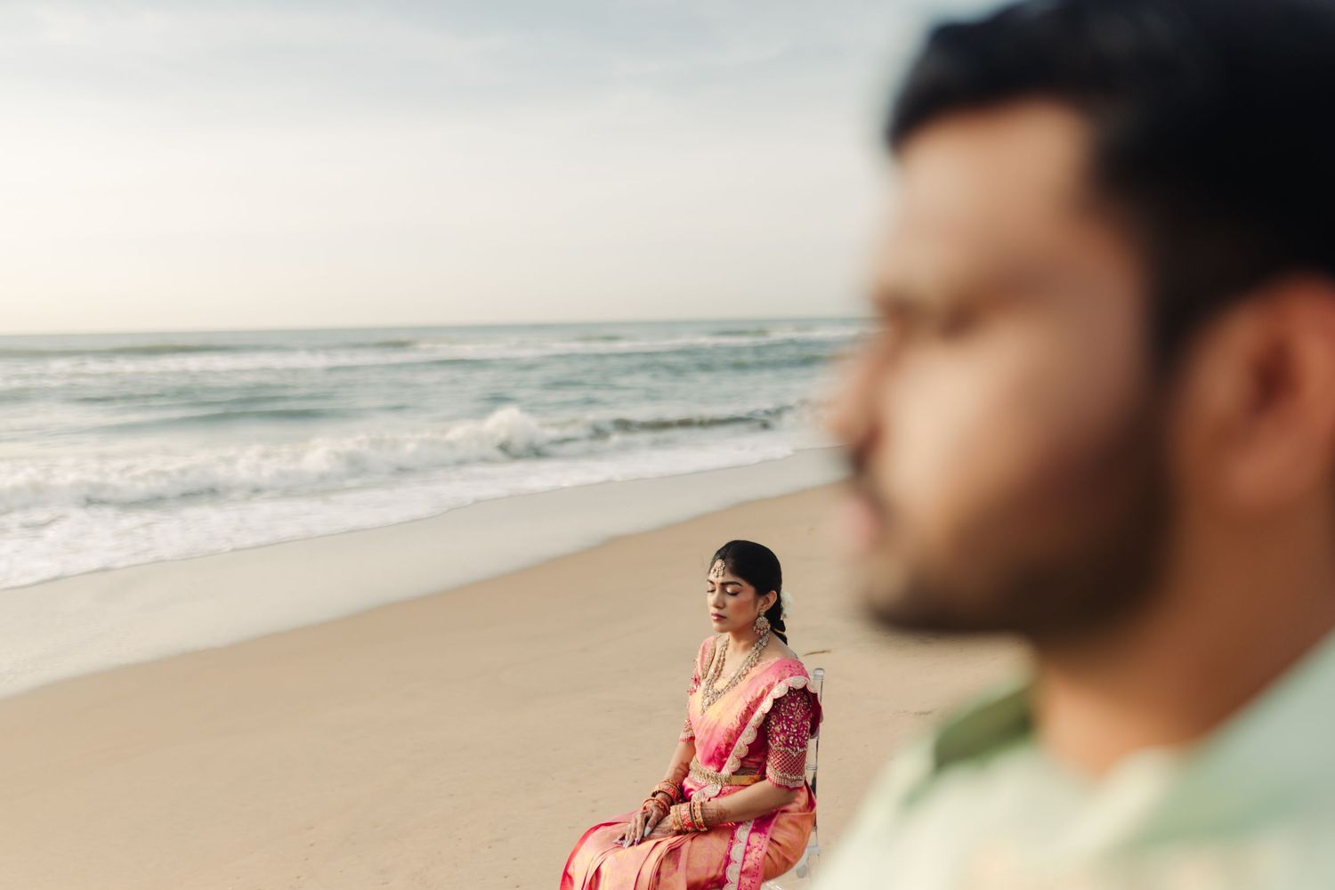 A couple shares a tender moment while walking along the shoreline at sunset.