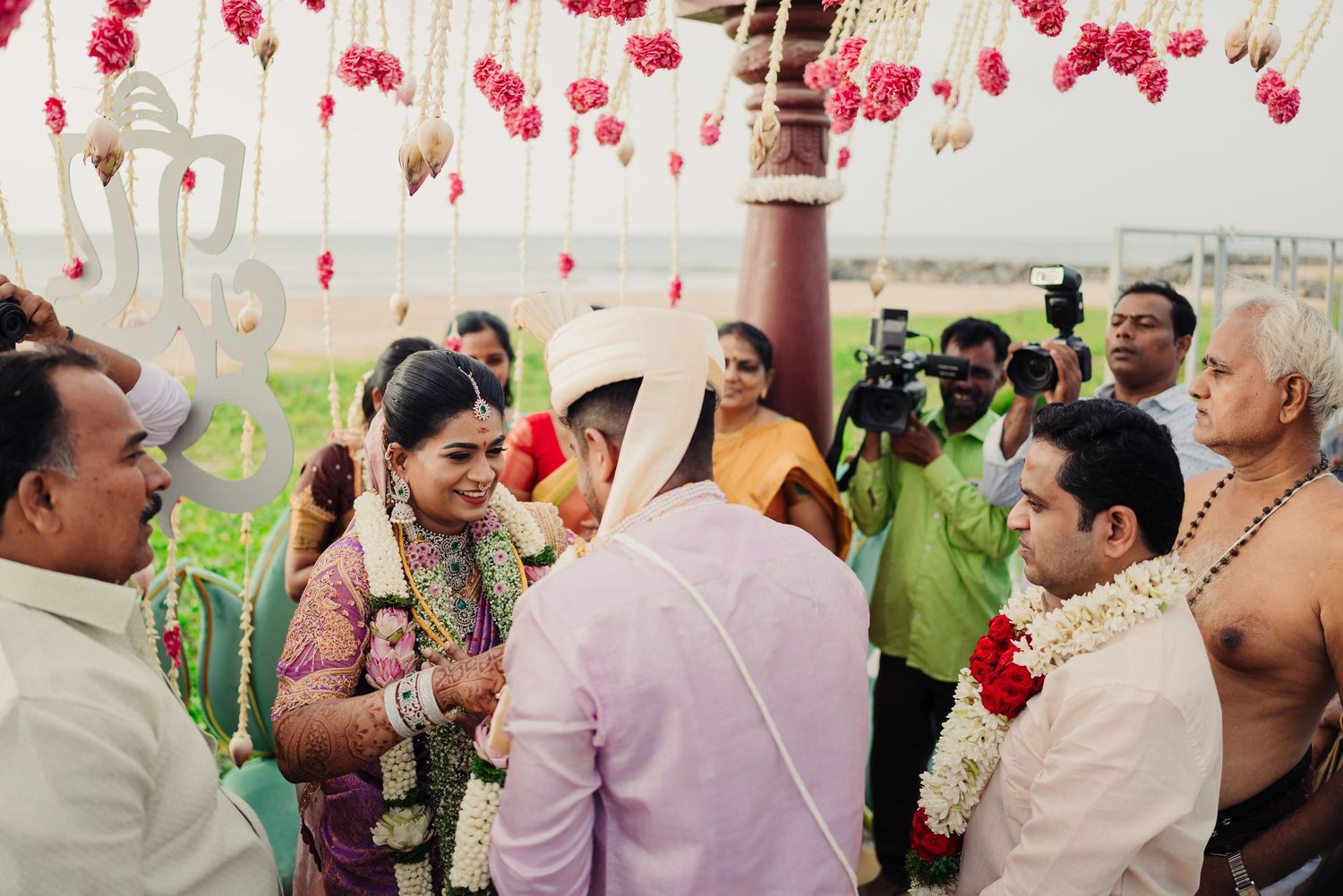 Wedding venue decorated with hanging red flowers and guests celebrating in traditional attire.
