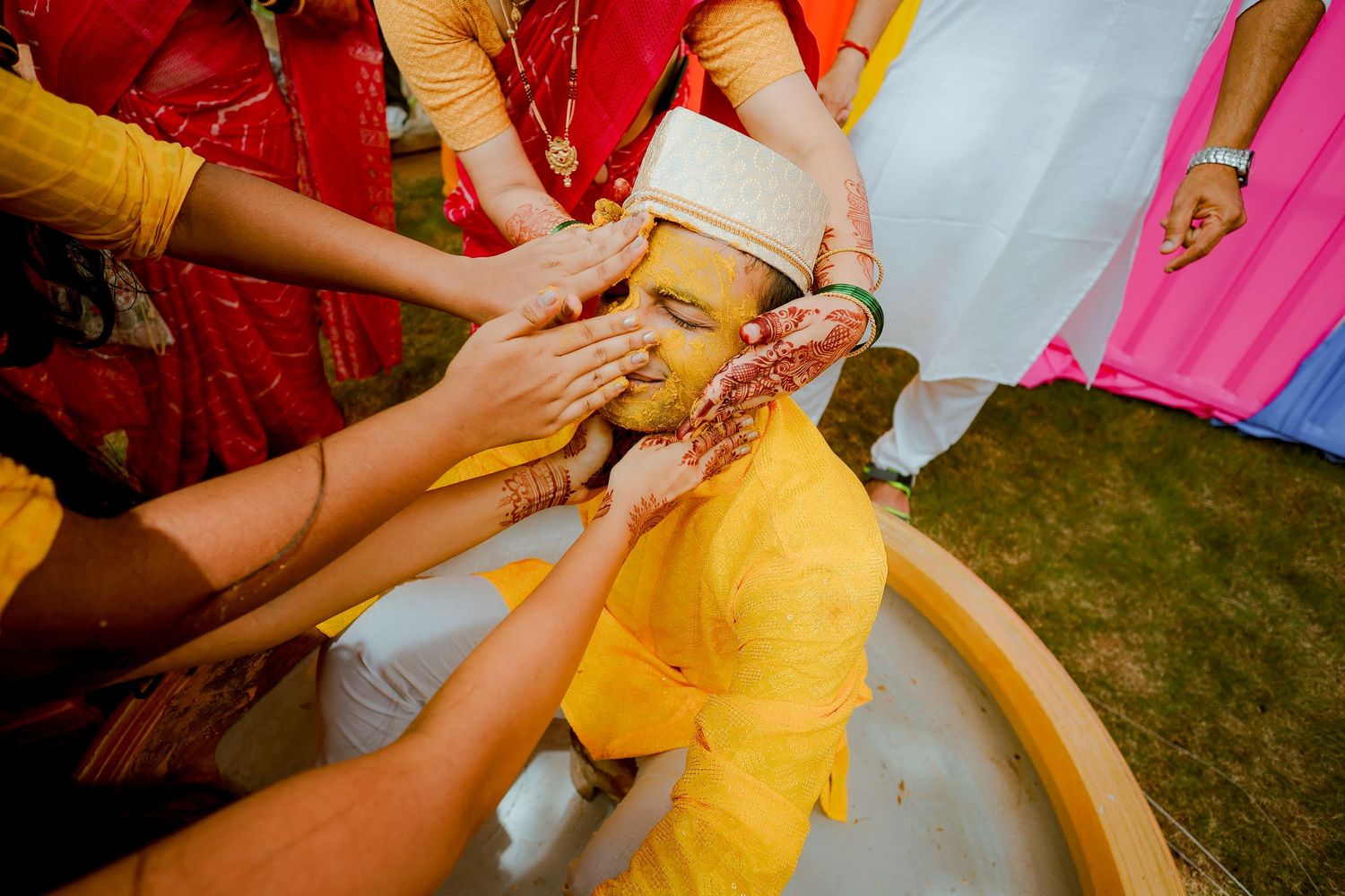 Hands work together to pin and adjust a bright yellow dress during a fitting or alteration session.