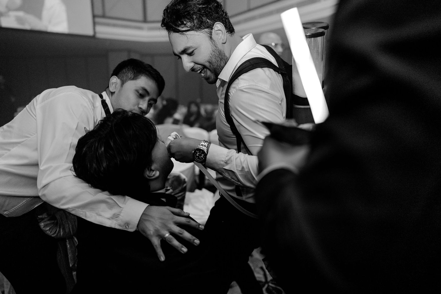 Black and white photo of groomsmen celebrating and dancing together at a wedding reception.