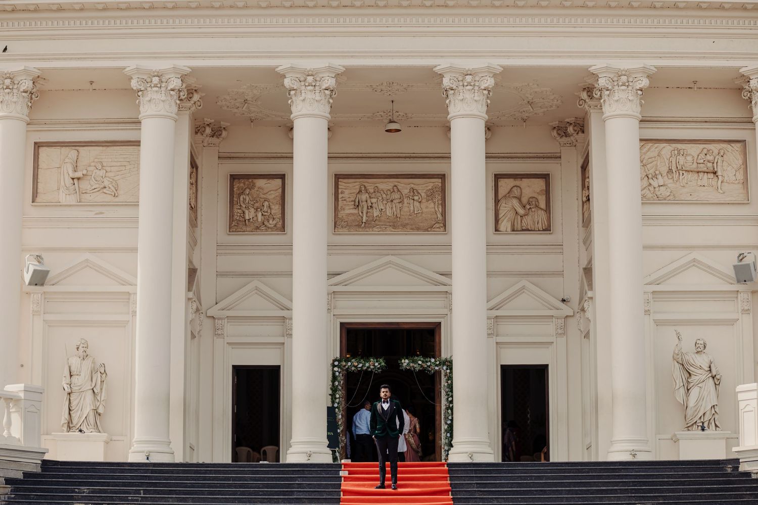 Exterior view of a grand neoclassical building with white columns and ornate architectural details.