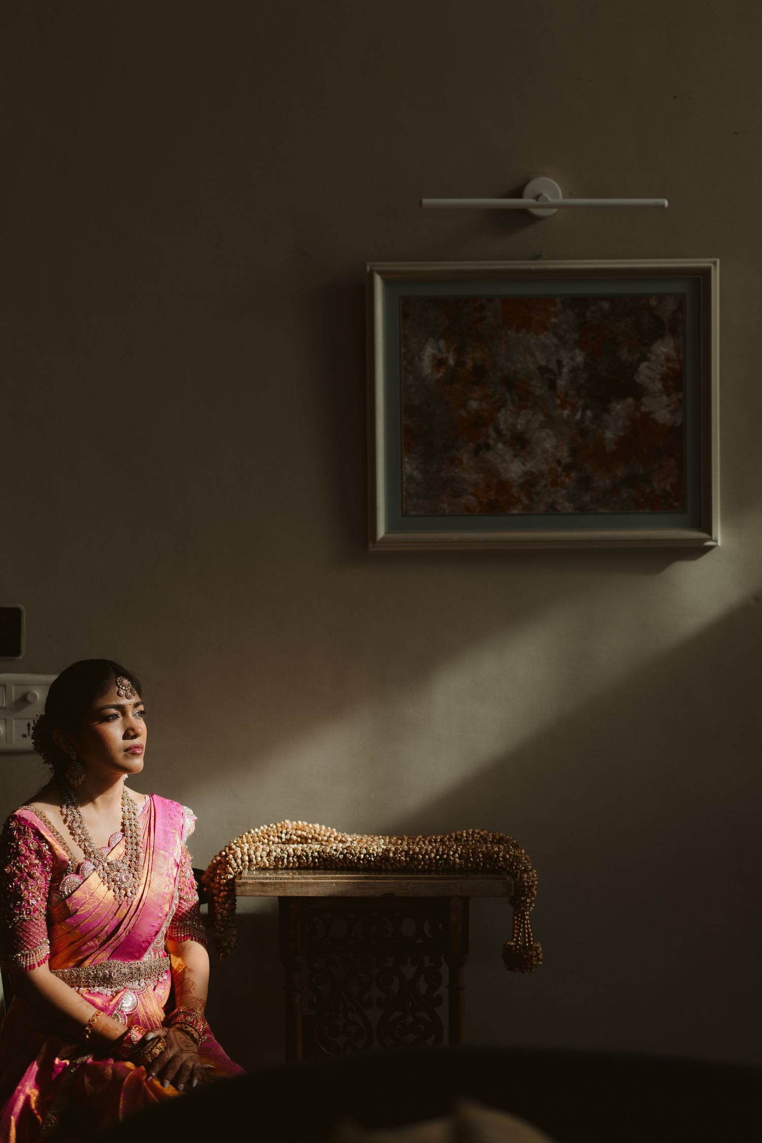 A sequence of dramatic portrait shots showing a person in pink traditional attire sitting on an ornate couch in moody lighting.