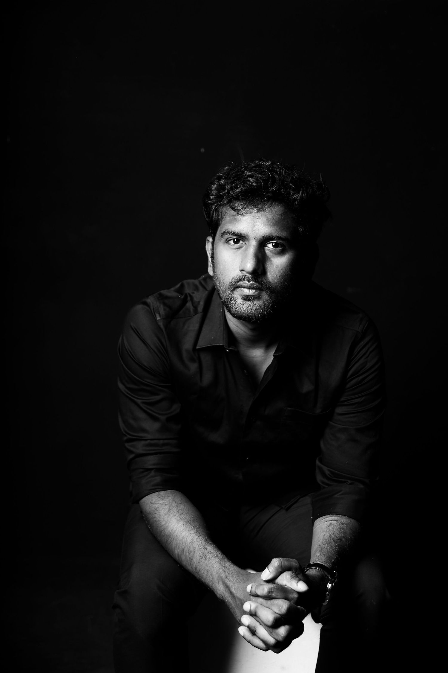 Dramatic low-key portrait series in black and white against dark background.