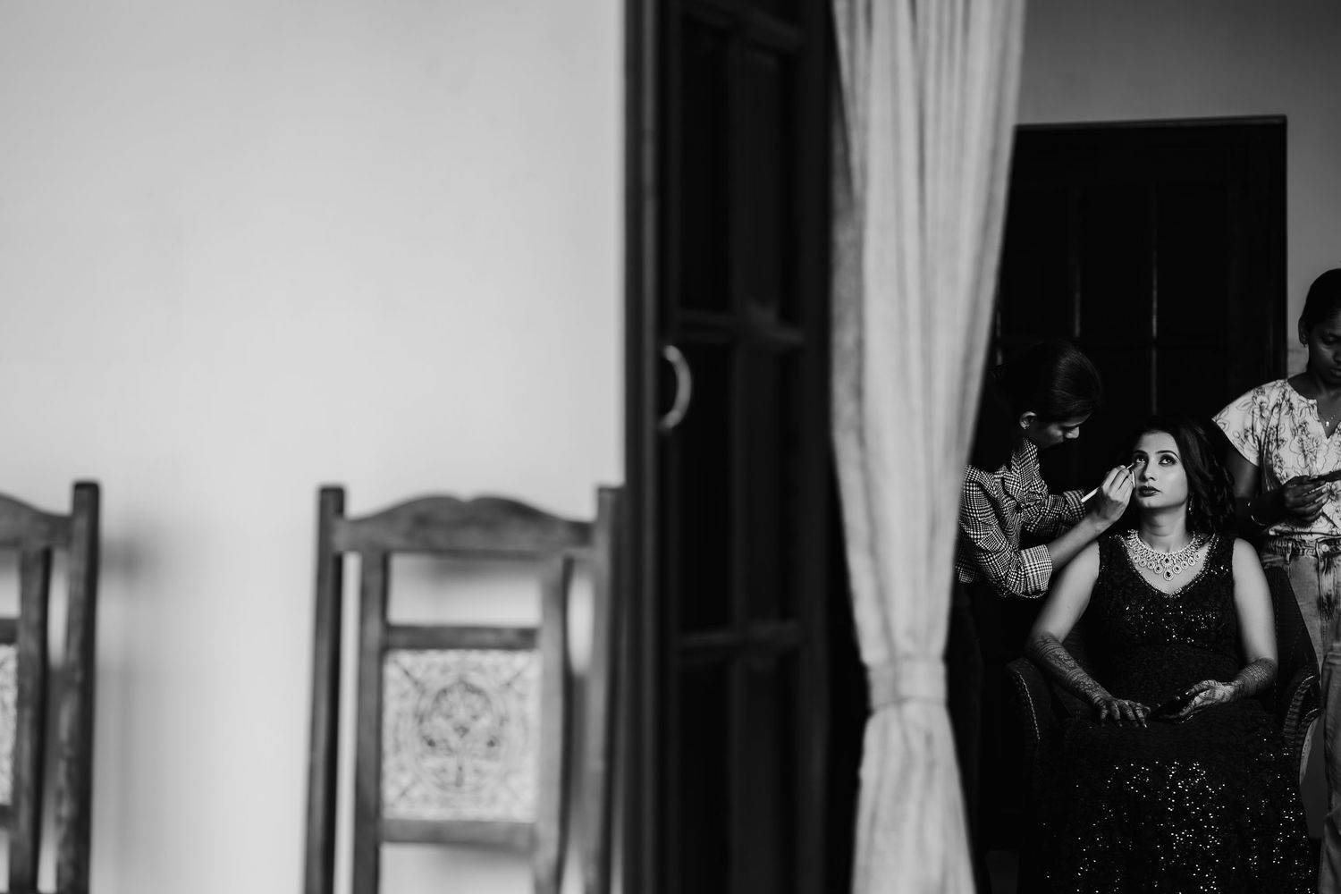 A black and white photo shows a person dancing alone in an empty room with white curtains and wooden floors.