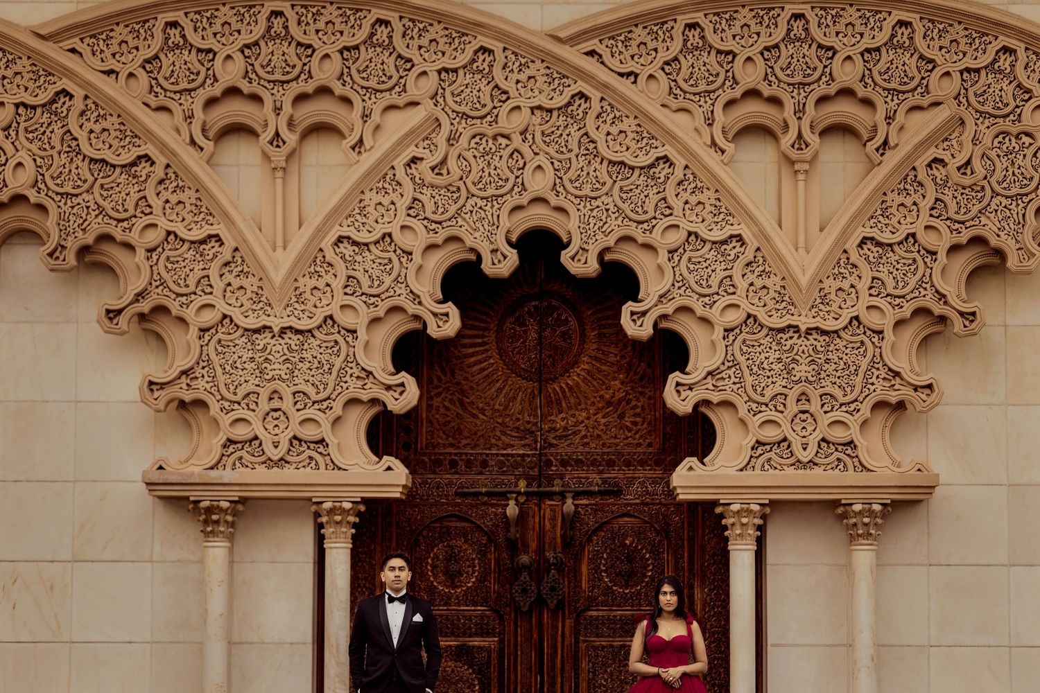 Ornate white archways with intricate Moorish architectural details line a corridor in a historic palace.