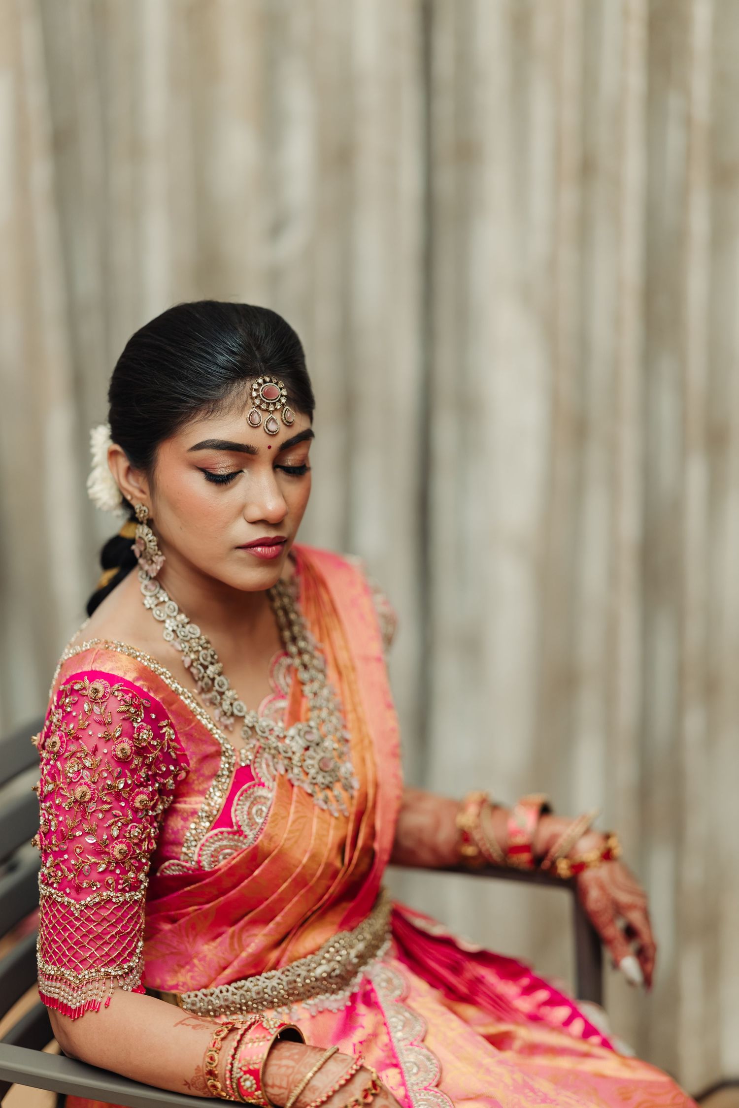 Traditional South Indian bride in red and peach silk saree with ornate embroidered details.