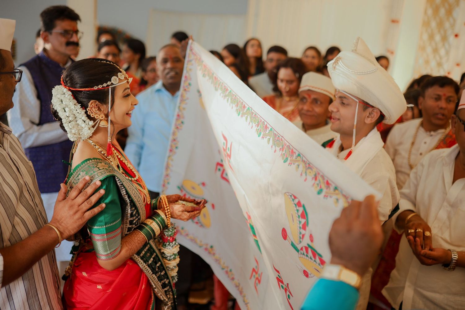 A group of people celebrating at an Indian wedding ceremony with traditional decorations and attire.