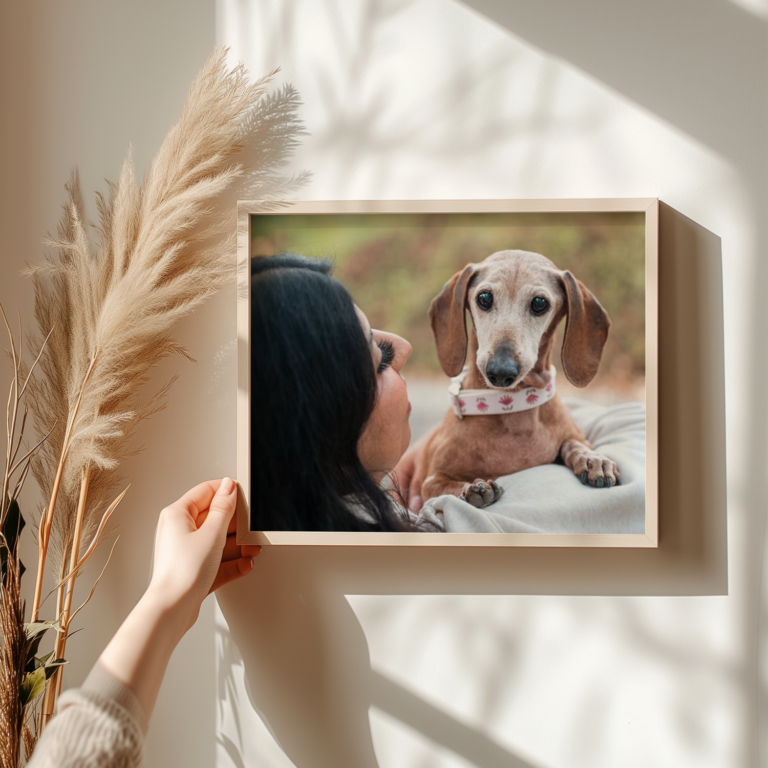 Decorative shelf display with framed dog photos and pampas grass in white vases.