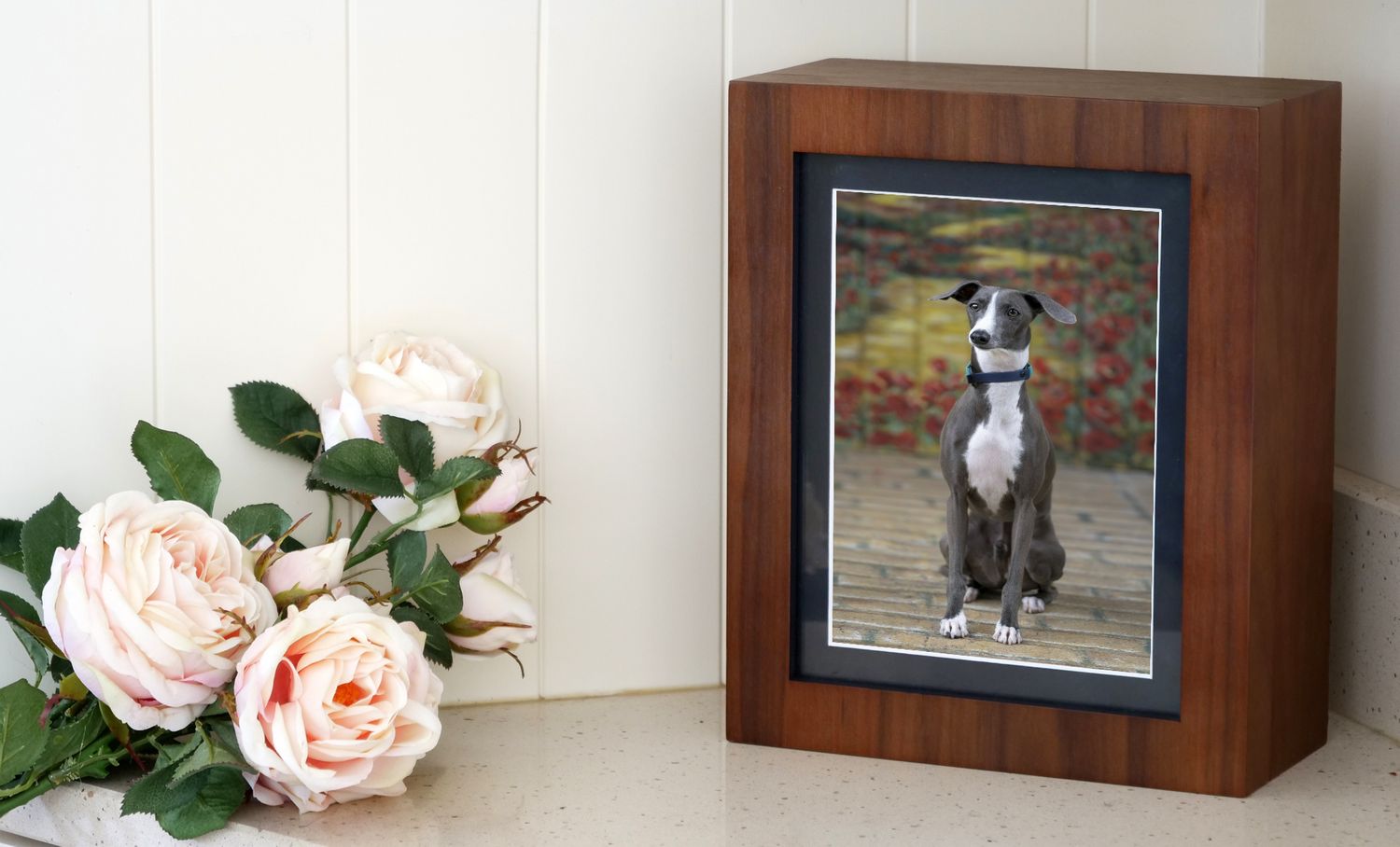 Gallery wall with framed dog photos and pink roses as decoration.