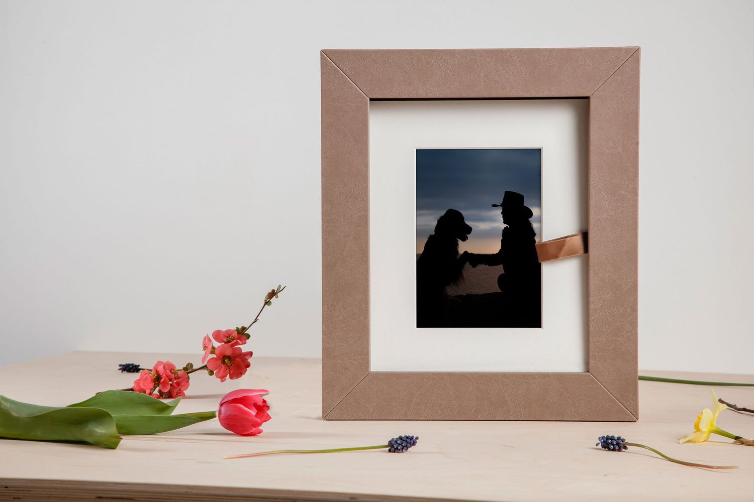 A framed silhouette photo sits on a table with pink flowers and decorative elements.