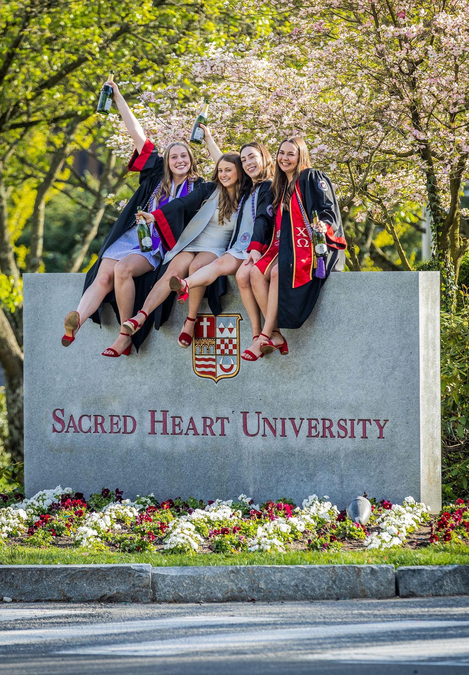 Group of graduates on Sacred Heart University entrance sign