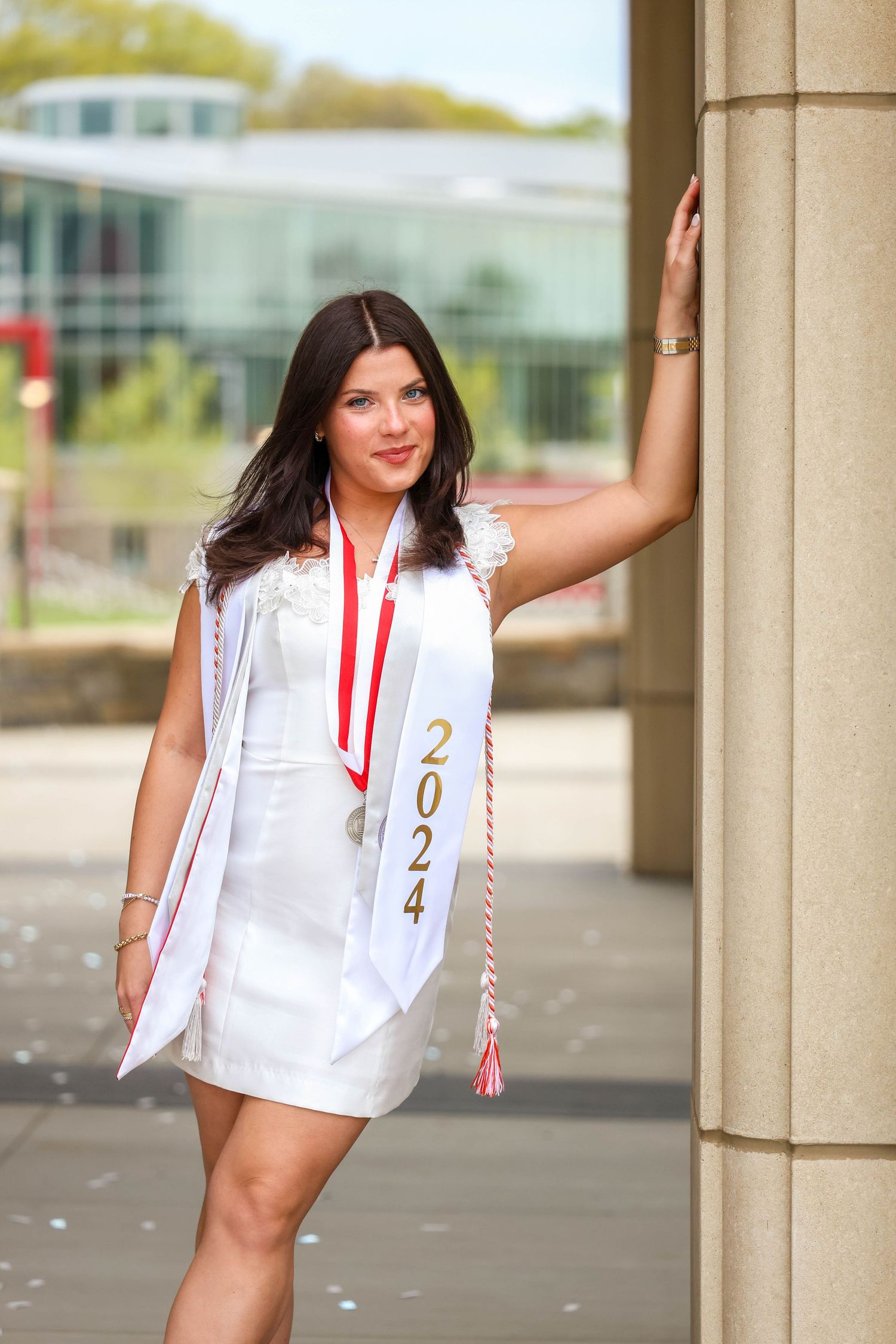 Graduate leaning against wall on Sacred Heart University Campus.