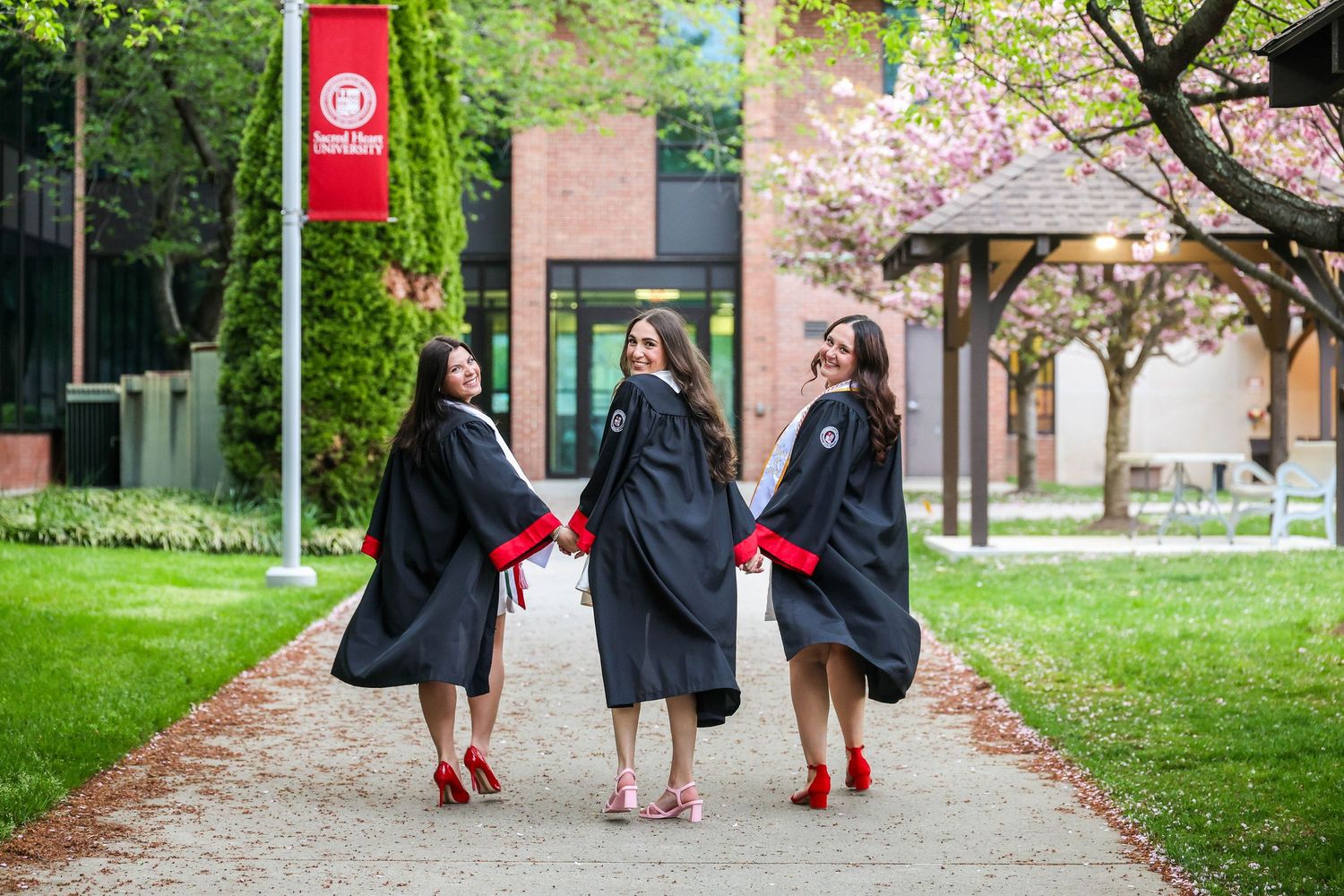 Graduates walking through a garden pathway in black caps and gowns.