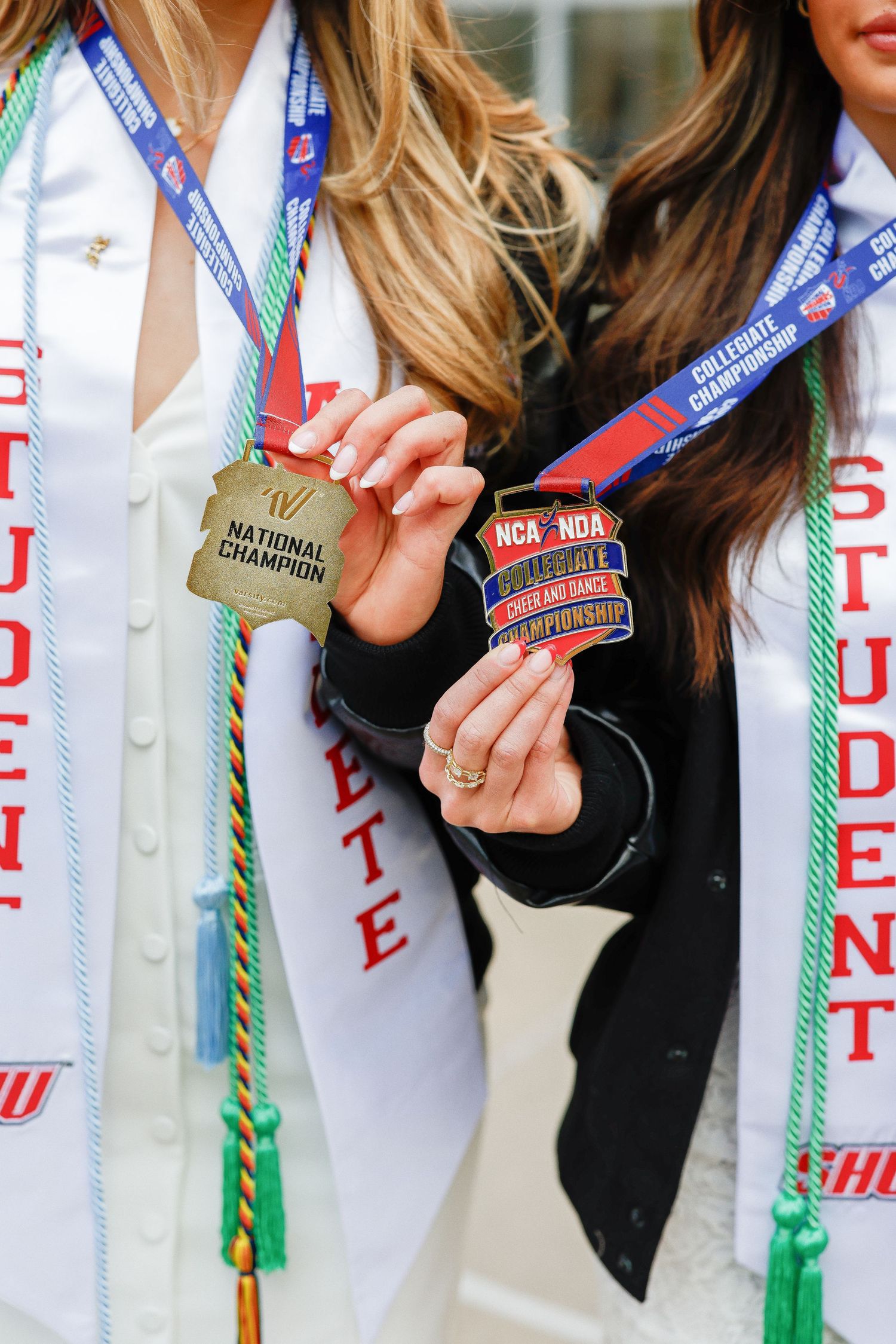 Close-up of graduation stoles and honor cords with university insignia and Greek letters.