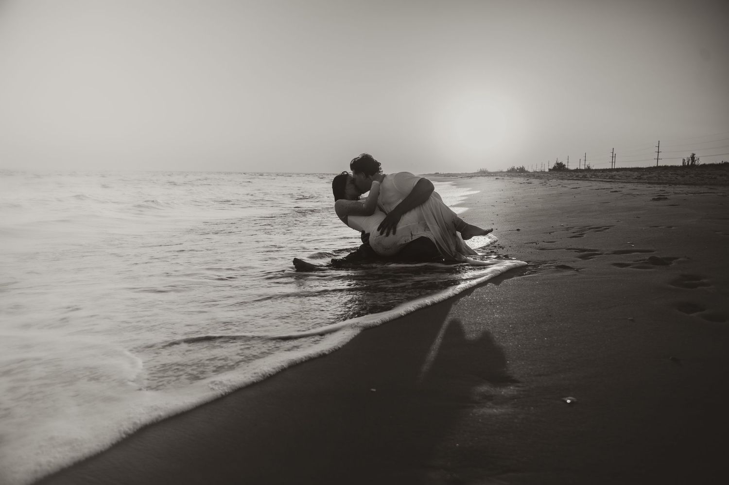 Black and white image of a romantic beach moment near the shoreline.