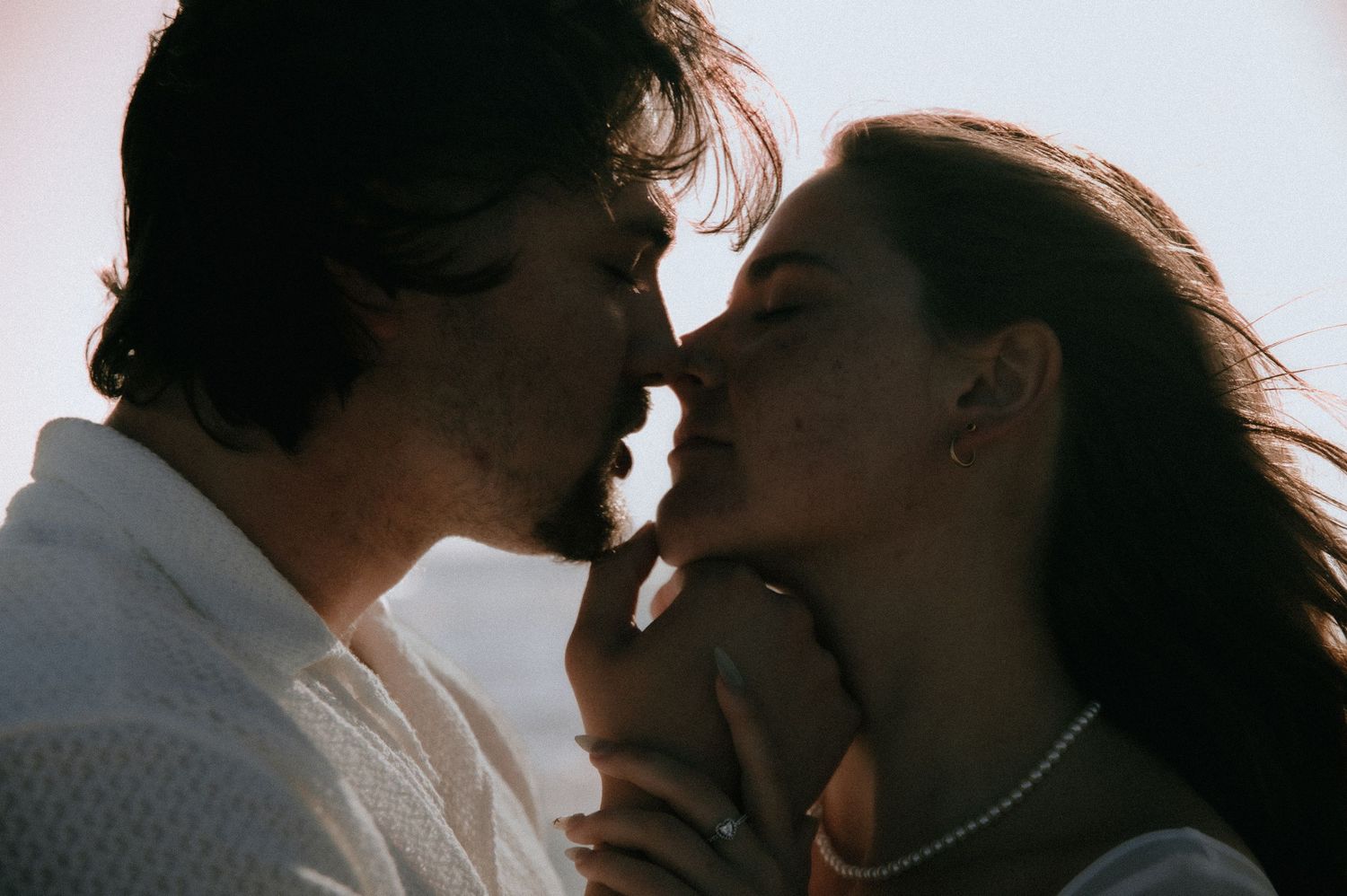 A close-up silhouette of two people sharing an intimate moment at sunset.