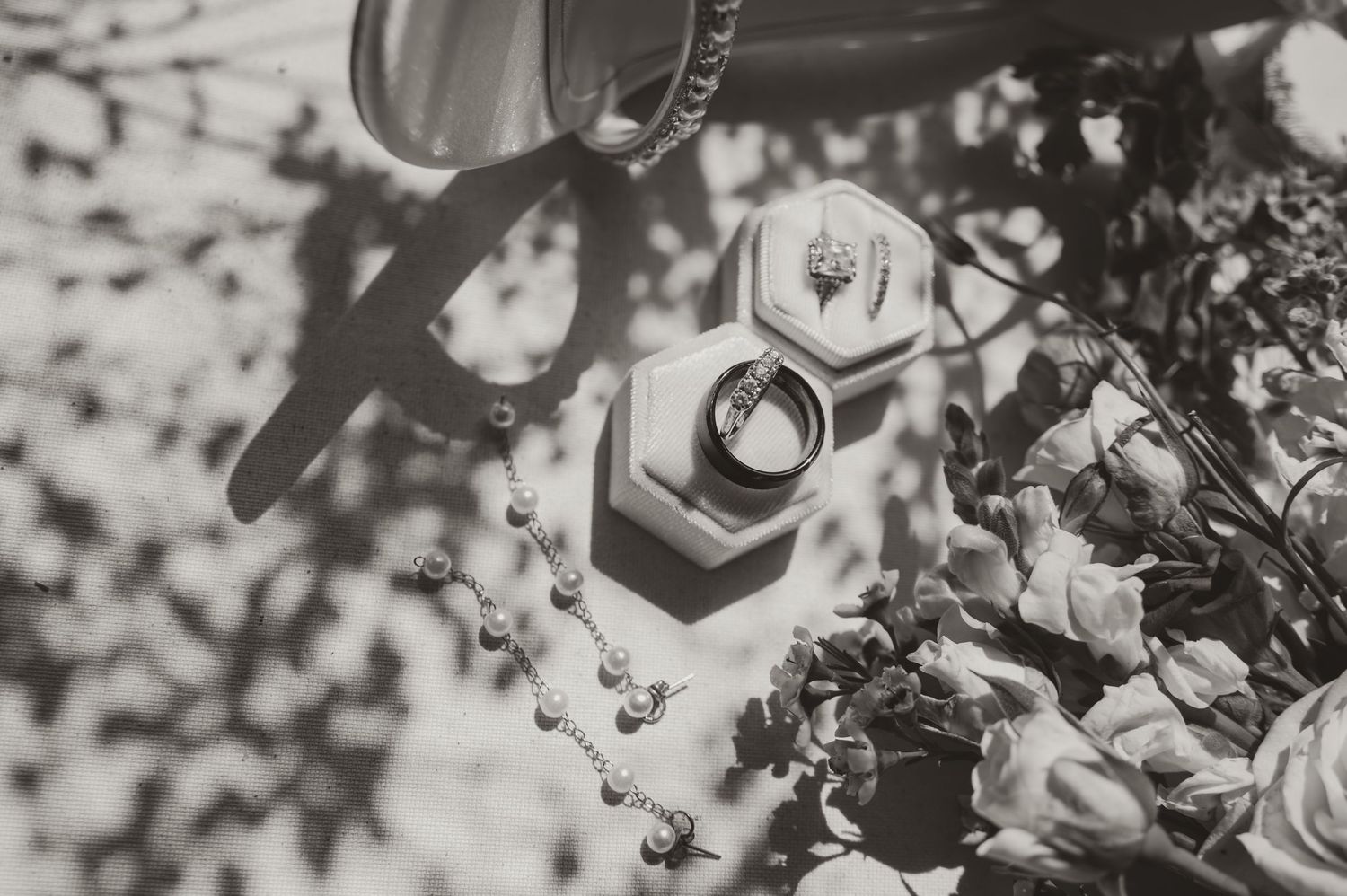 Black and white still life photograph showing two hexagonal jars amid flowers and shadows.