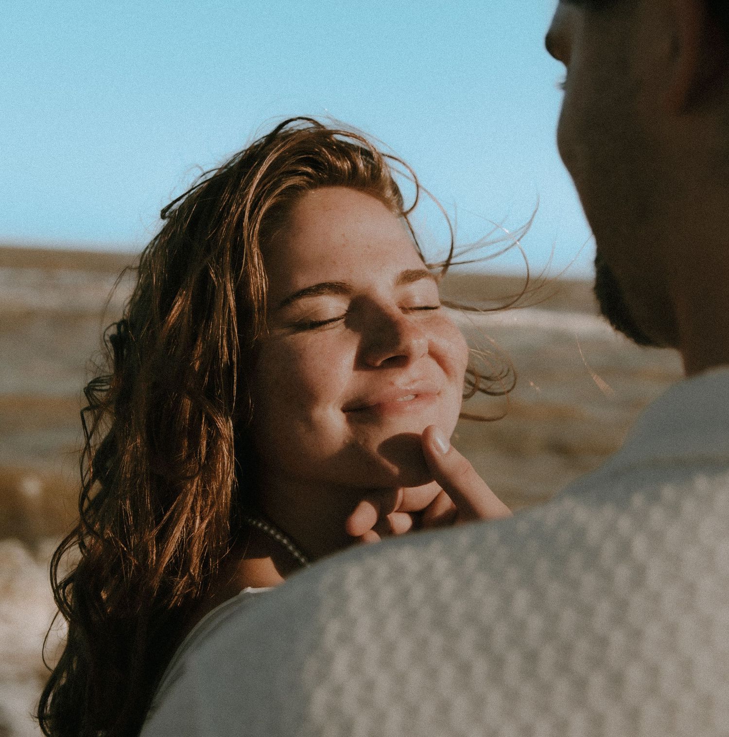 A tender romantic moment captured in warm sunlight as a couple shares an intimate connection outdoors.